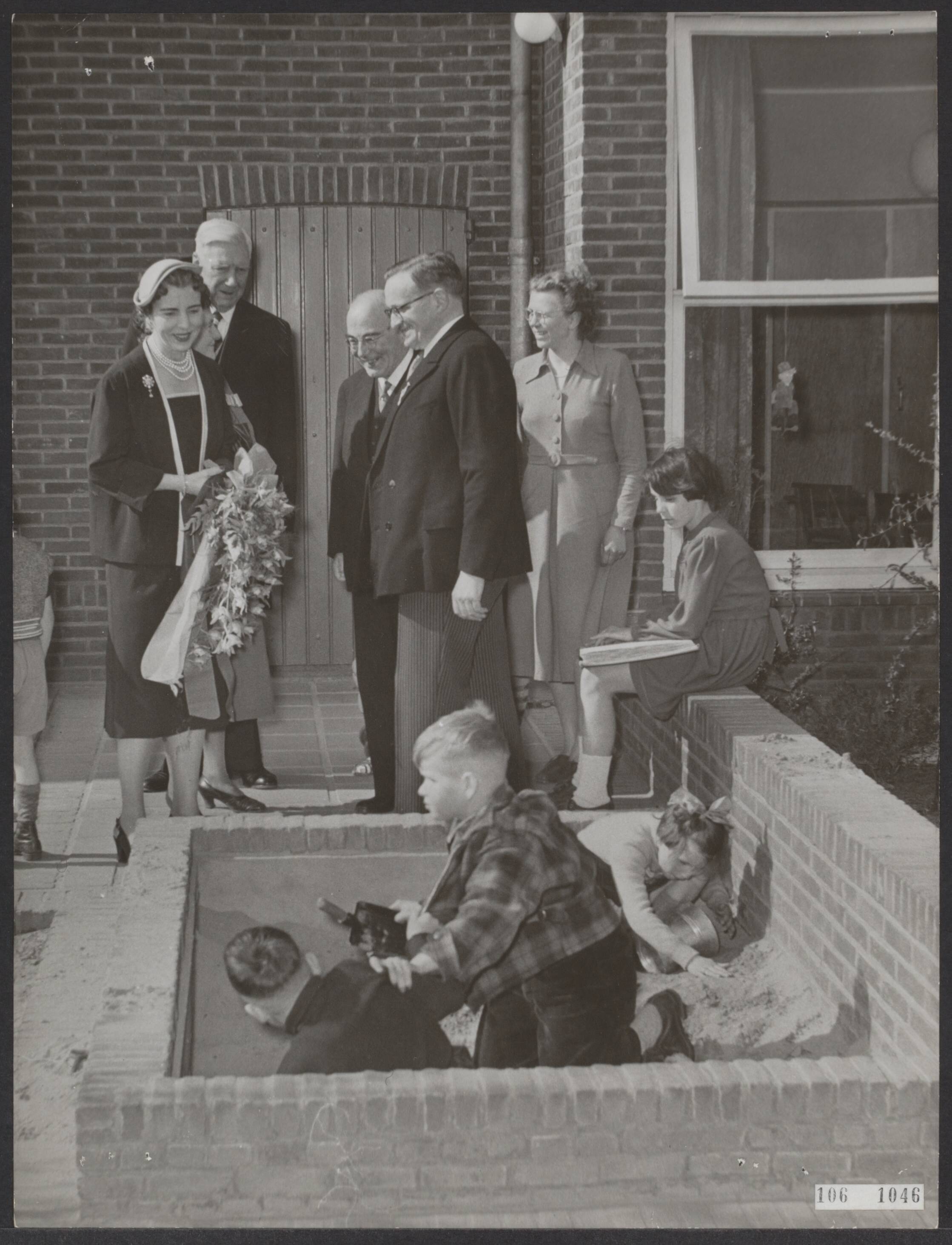 Fotocollectie Elsevier Binnenland — Staatsbezoek van het Deense koningspaar aan ons land van 26 tot en met 28 april 1954. Bezoek van koningin Ingrid en koningin Juliana aan het Blindeninstituut te Huizen. Koningin Ingrid bij de kinderen terwijl ze in de zandbak spelen — Foto: Noske, J.D. / Anefo. Licentie: Set B: Rechtenvrij / Publiek Domein. Bron: Nationaal Archief. http://hdl.handle.net/10648/ae2f254a-d0b4-102d-bcf8-003048976d84