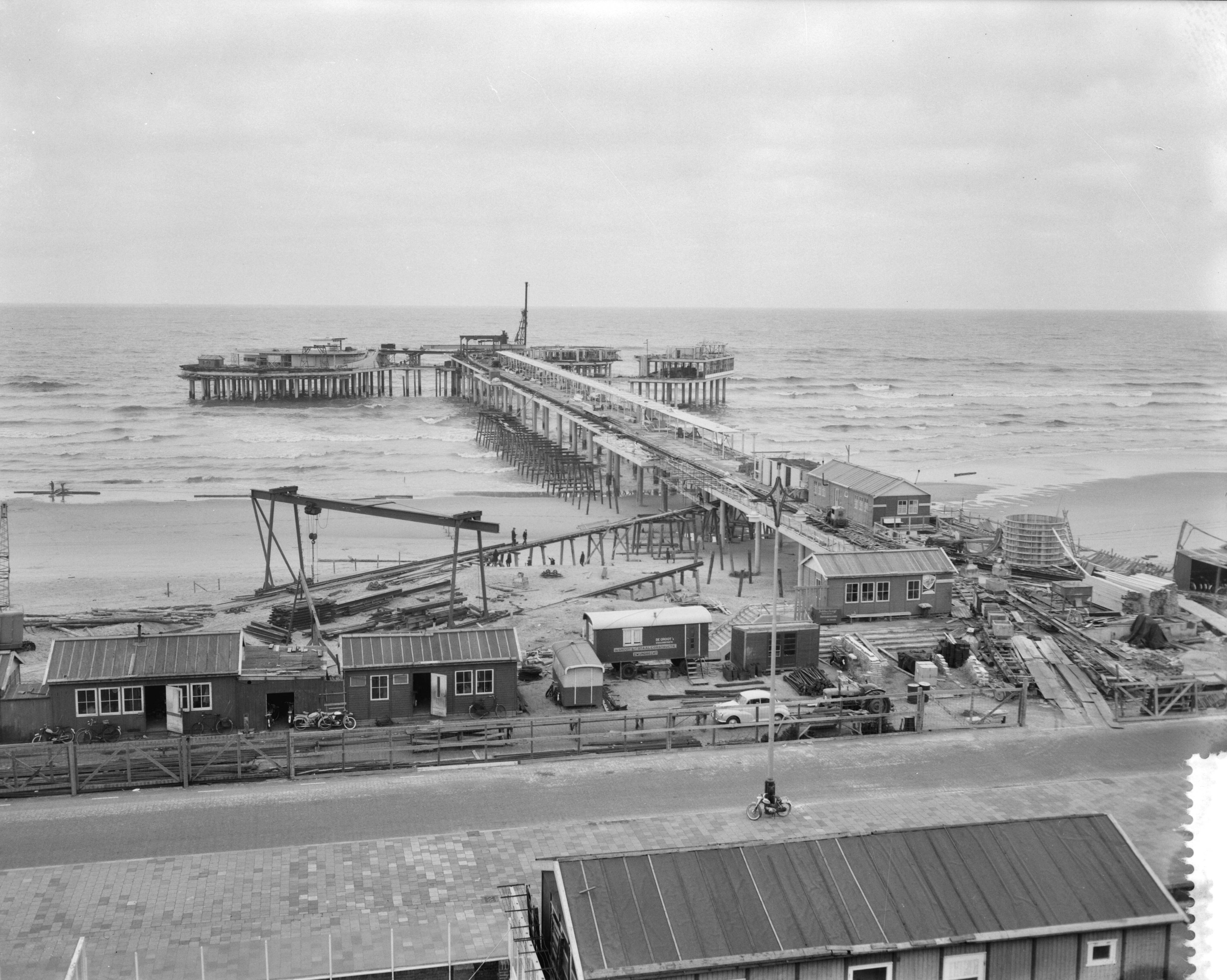 Fotocollectie Anefo — Voorbereidingen strandseizoen in Scheveningen. Overzicht van de in aanbouw zijnde Pier — Foto: Bilsen, Joop van / Anefo. Licentie: Set B: Rechtenvrij / Publiek Domein. Bron: Nationaal Archief. http://hdl.handle.net/10648/a9cb3ac0-d0b4-102d-bcf8-003048976d84