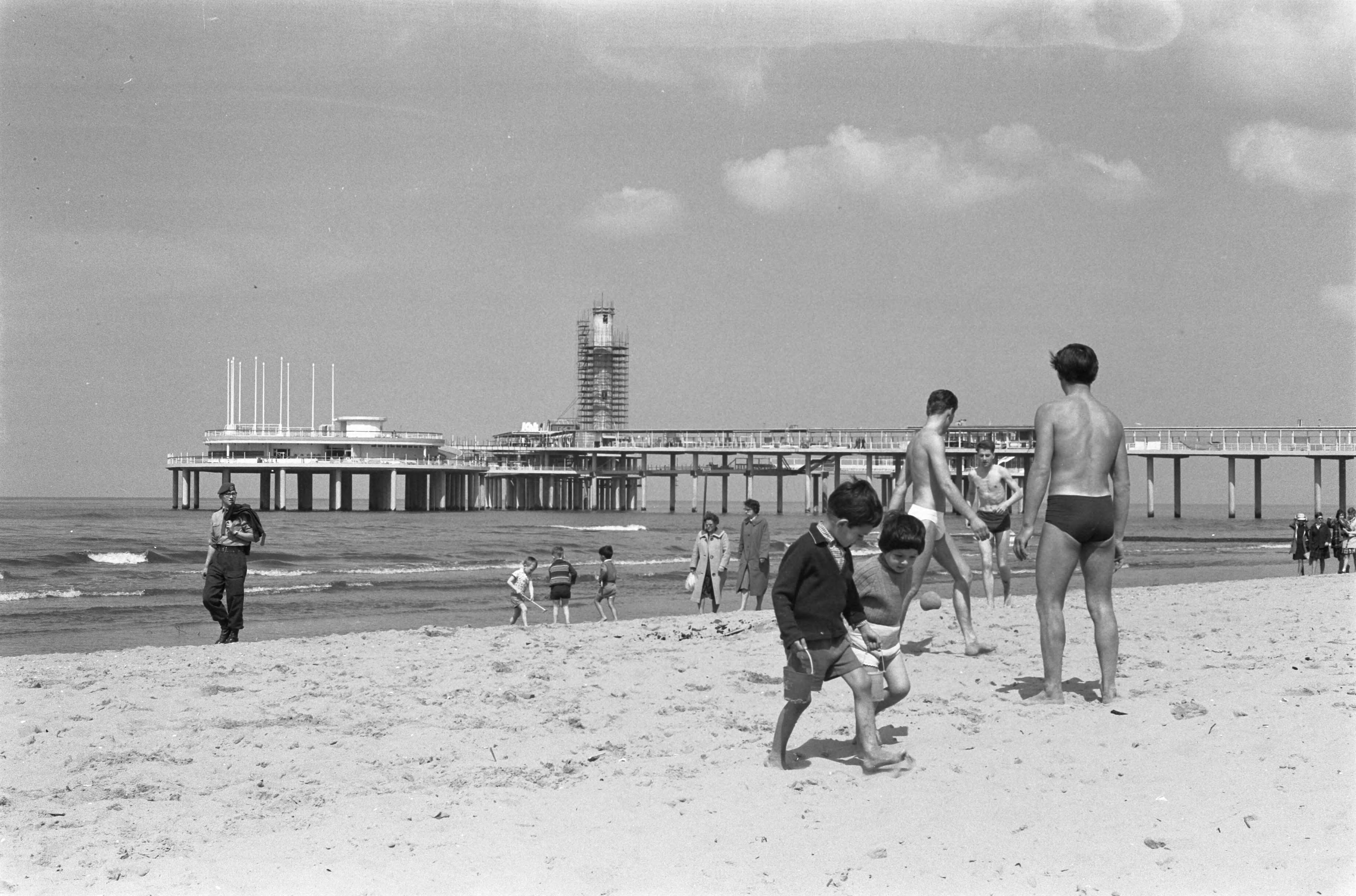 Fotocollectie Anefo — De nieuwe Pier in Scheveningen. Strandbeeld met in de achtergrond de nieuwe pier in aanbouw — Foto: Pot, Harry / Anefo. Licentie: Set B: Rechtenvrij / Publiek Domein. Bron: Nationaal Archief. http://hdl.handle.net/10648/a9d2dfa0-d0b4-102d-bcf8-003048976d84