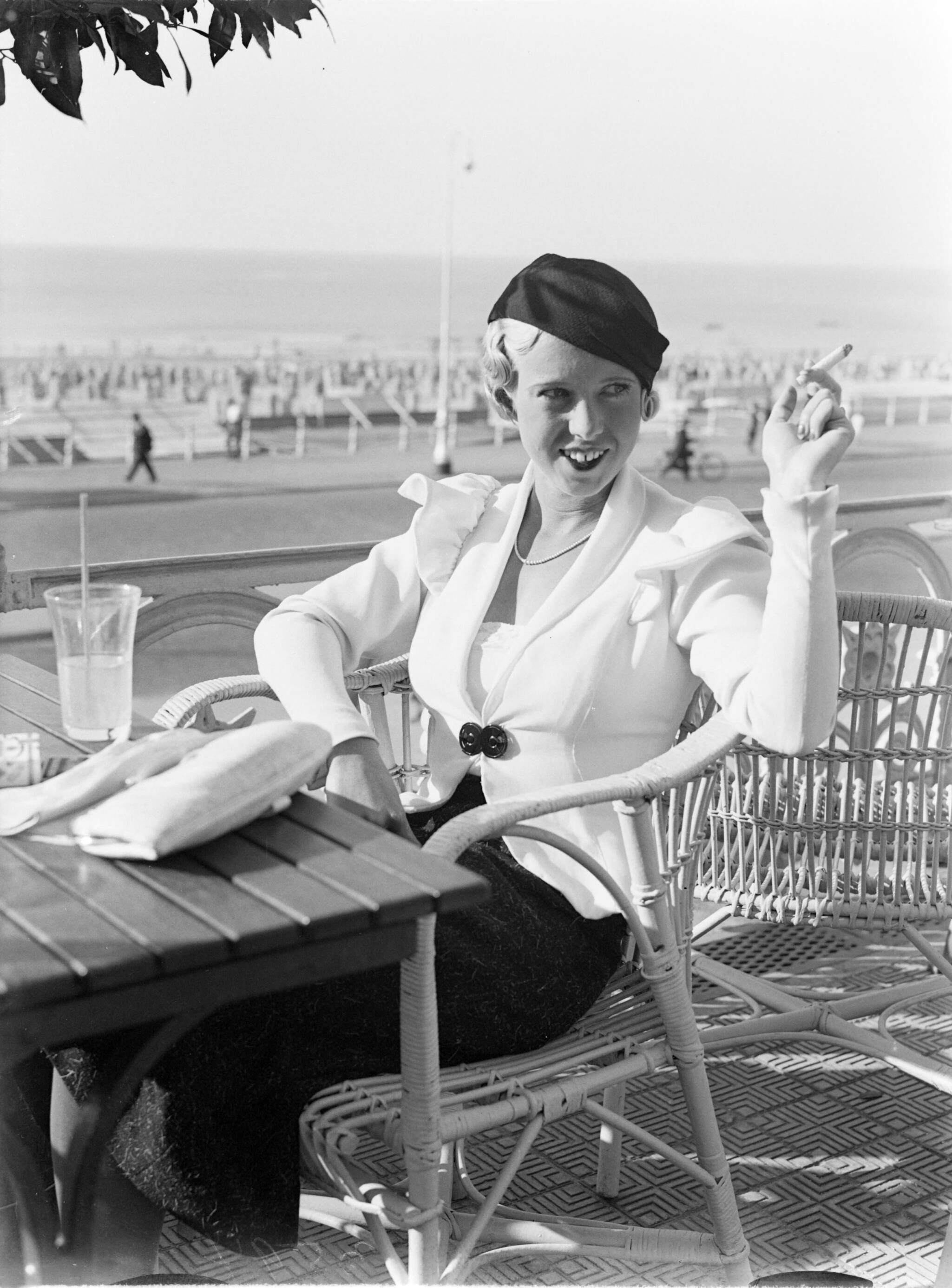 Scheveningen. — Een vrouw (Yvonne?) rookt een sigaret op de boulevard van Scheveningen — Foto: Poll, Willem van de. Licentie: Set B: Rechtenvrij / Publiek Domein. Bron: Nationaal Archief. http://hdl.handle.net/10648/ae9aa9d2-d0b4-102d-bcf8-003048976d84