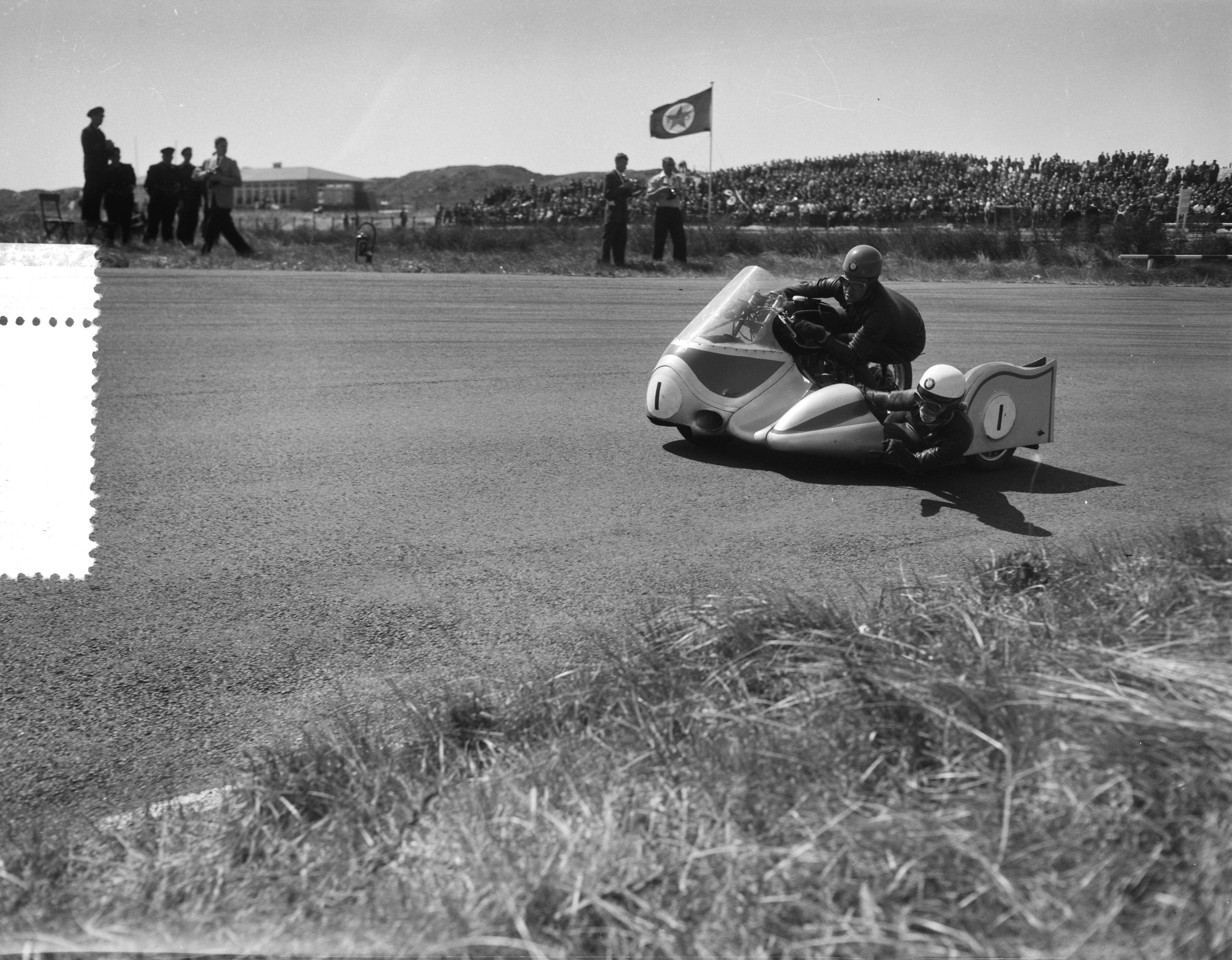 Fotocollectie Anefo — Zijspanrace op het circuit van Zandvoort. Jacques Drion (met bakkeniste Ingeborg Stoll) (Frankrijk/Duitsland) — Foto: Bilsen, Joop van / Anefo. Licentie: Set B: Rechtenvrij / Publiek Domein. Bron: Nationaal Archief. http://hdl.handle.net/10648/a948a132-d0b4-102d-bcf8-003048976d84