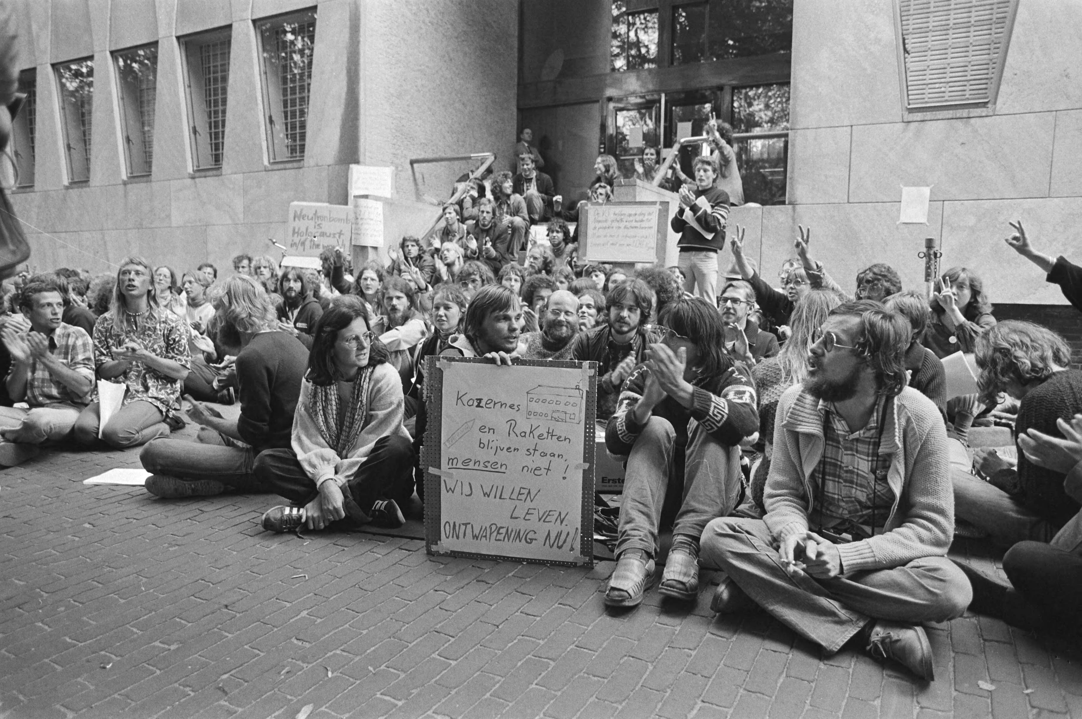 Demonstratie voor de VS-ambassade in Den Haag in verband met de productie van de neutronenbom — Demonstranten voor de ambassade — Foto: Dijk, Hans van / Anefo. Licentie: Set B: Rechtenvrij / Publiek Domein. Bron: Nationaal Archief. http://hdl.handle.net/10648/ad014dce-d0b4-102d-bcf8-003048976d84