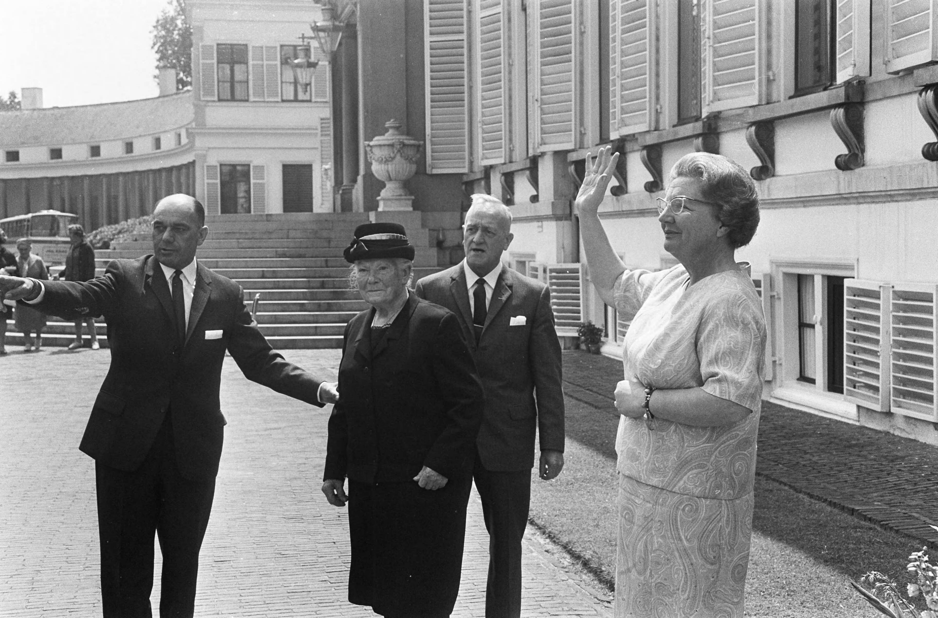 Koningin Juliana ontvangt ouden van dagen op Paleis Soestdijk — De koningin zwaait. Een bejaarde vrouw met naast zich een wijzende man — Foto: Fotograaf Onbekend / Anefo. Licentie: Set B: Rechtenvrij / Publiek Domein. Bron: Nationaal Archief. http://hdl.handle.net/10648/ab1c65e8-d0b4-102d-bcf8-003048976d84