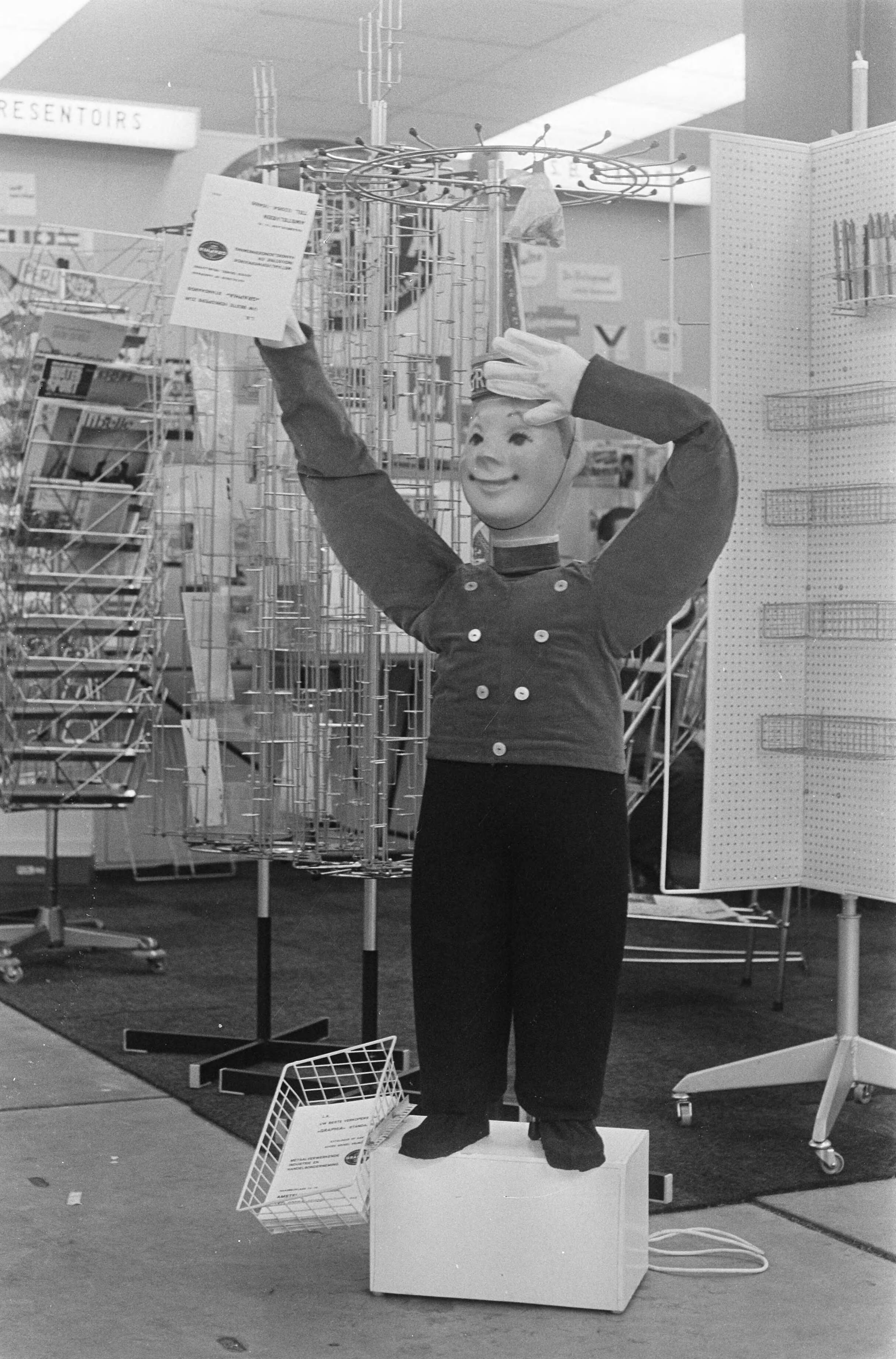 Fotocollectie Anefo — Expositie zelfbediening 1967 te Utrecht, een vacuummannetje deelt folders uit — Foto: Merk, Ben / Anefo. Licentie: Set B: Rechtenvrij / Publiek Domein. Bron: Nationaal Archief. http://hdl.handle.net/10648/ab196618-d0b4-102d-bcf8-003048976d84
