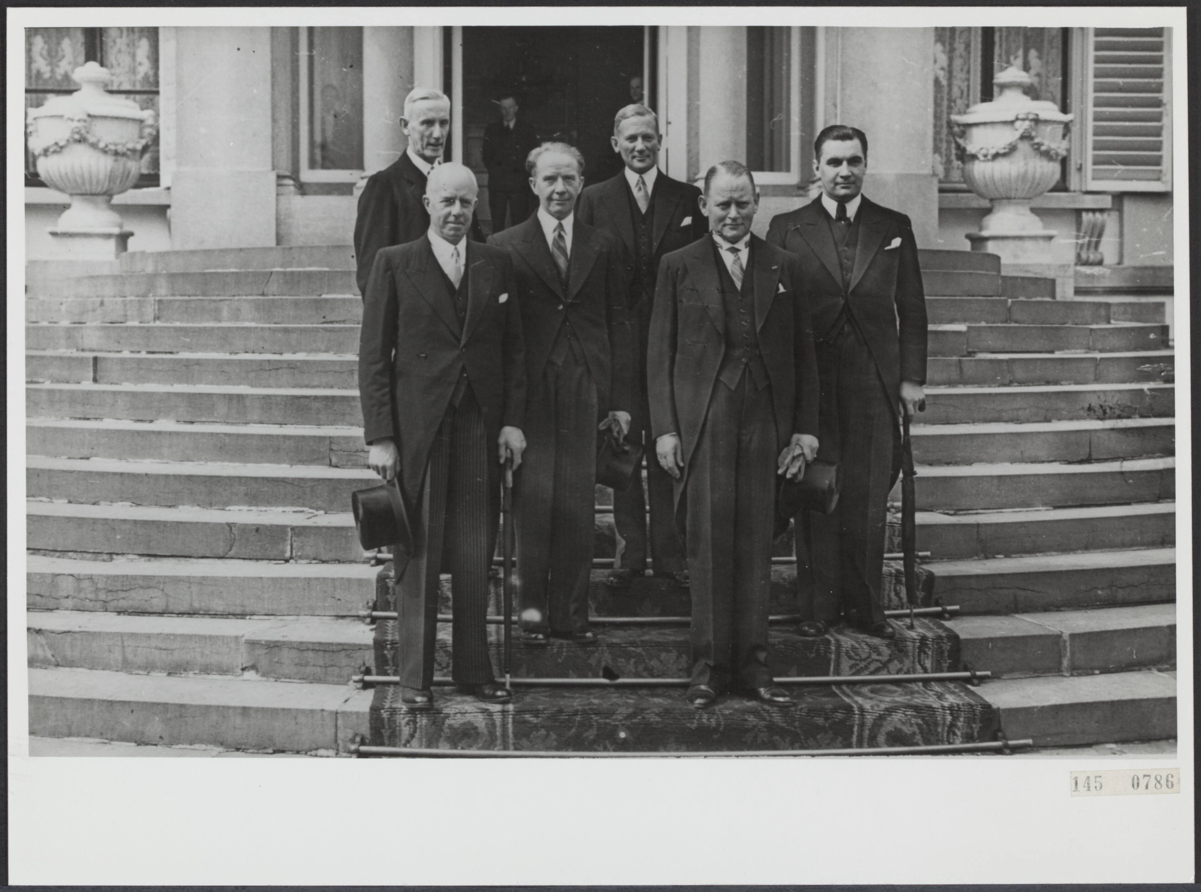 Fotocollectie Rijksvoorlichtingsdienst Eigen — Kabinet Drees I (1948-1951). Ministers op het bordes van paleis Soestdijk na beediging door prinses Juliana. Vlnr. A.M Joekes, Th. R. J. Wijers, F.J.Th. Rutten, W.F. Schokking, D.U. Stikker en E.M.J. A. Sassen — Foto: ANP / RVD of rechtenvrij. Licentie: Set B: Rechtenvrij / Publiek Domein. Bron: Nationaal Archief. http://hdl.handle.net/10648/af745574-d0b4-102d-bcf8-003048976d84