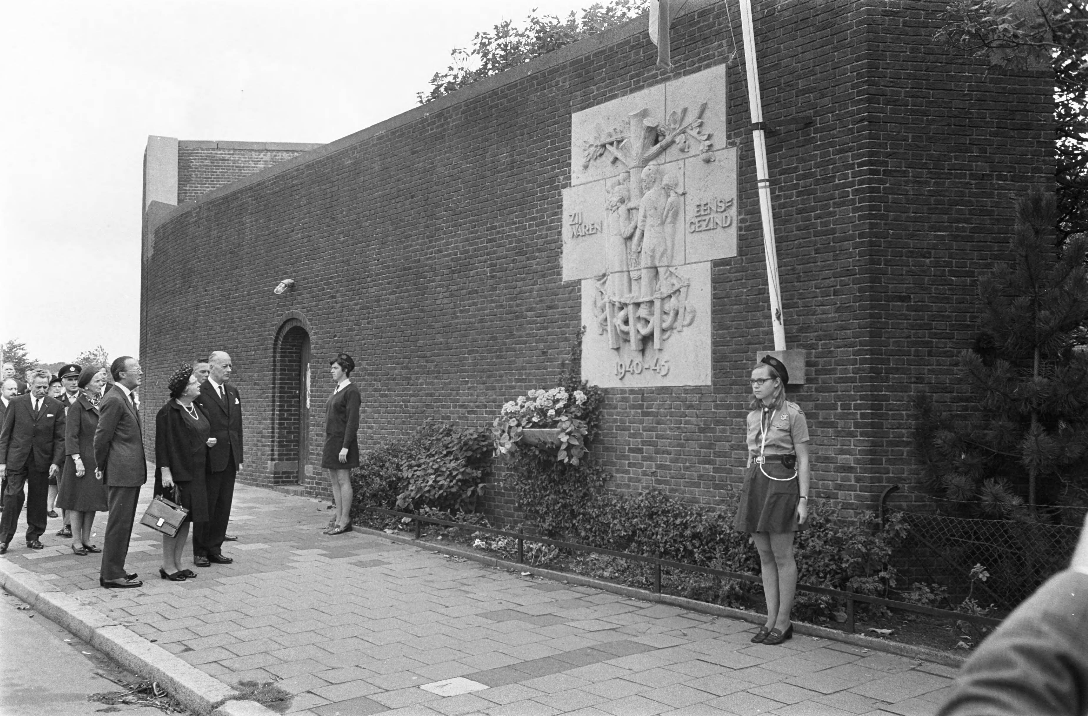 Fotocollectie Anefo — Koningin Juliana en prins Bernhard zijn bij de 25e dodenherdenking in de Scheveningse gevangenis (het Oranjehotel) bij 'Dodencel 601'; defilé langs het oorlogsmonument aan de muur van de gevangenis — Foto: Koch, Eric / Anefo. Licentie: Set B: Rechtenvrij / Publiek Domein. Bron: Nationaal Archief. http://hdl.handle.net/10648/aba31002-d0b4-102d-bcf8-003048976d84