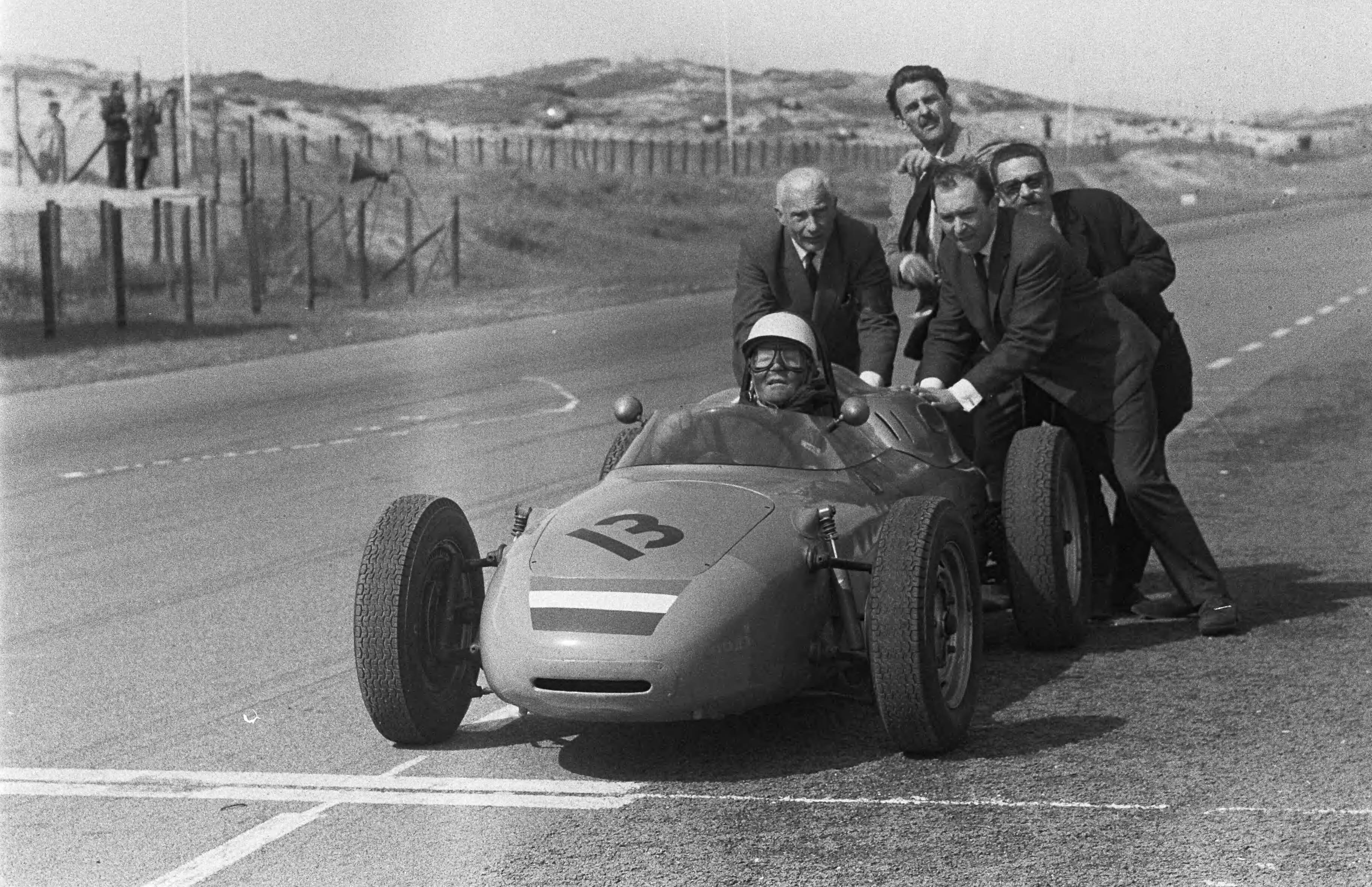Grand Prix Zandvoort 1962 — Trainingsritten voor de Grand Prix van Zandvoort. Carel Godin de Beaufort wordt door vier mannen aangeduwd in een Porsche 787 met nummer 13 — Foto: Bilsen, Joop van / Anefo. Licentie: Set B: Rechtenvrij / Publiek Domein. Bron: Nationaal Archief. http://hdl.handle.net/10648/aa08fdec-d0b4-102d-bcf8-003048976d84