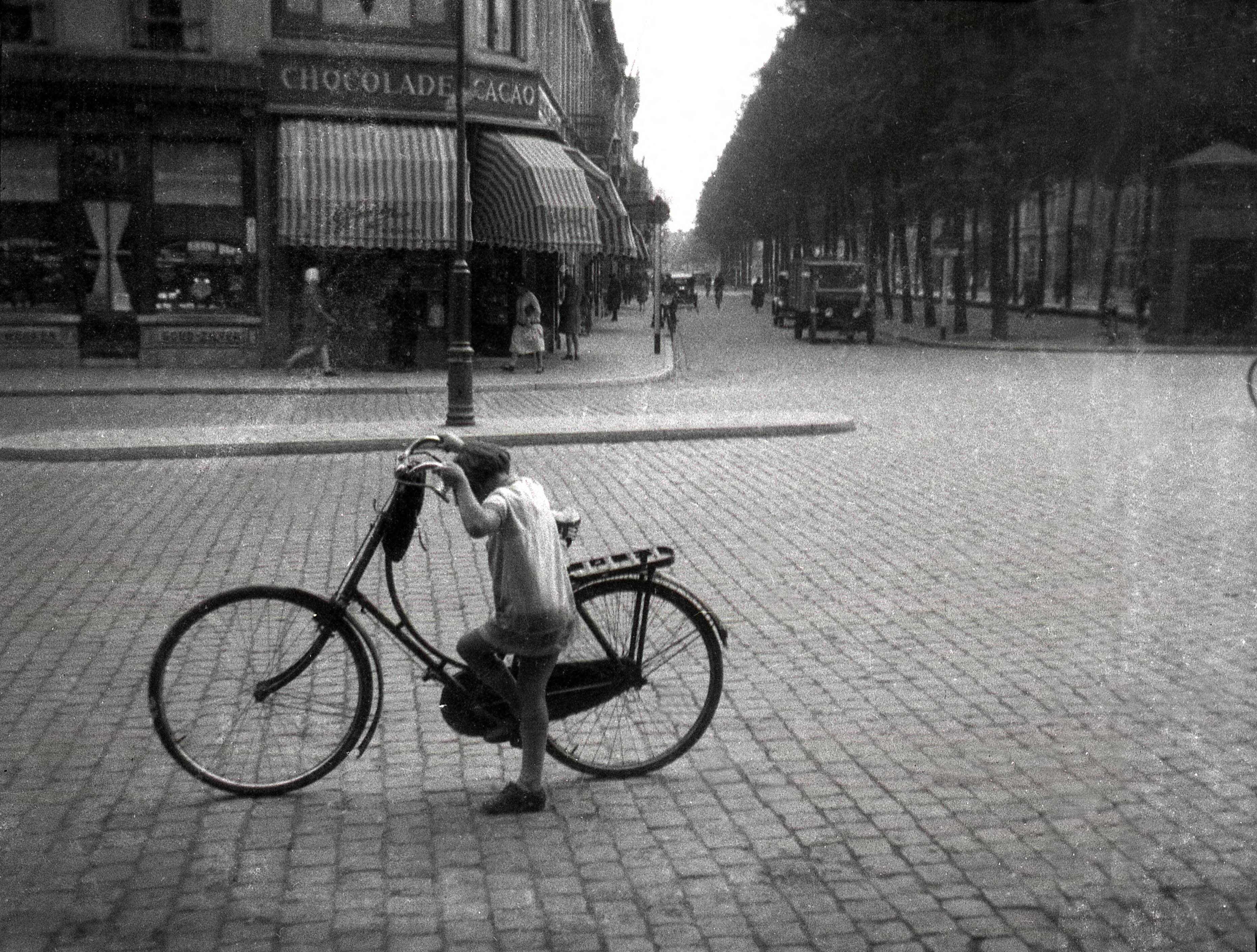 Portretten, Verkeer, "Topografie, plaatsen op naam" — Fietsen in Nederland. Een meisje staat met een damesfiets (opoefiets) op het met kinderhoofdjes geplaveide Van Coothplein te Breda. Omstreeks 1928. De foto is afkomstig uit de collectie van portretfotograaf bekend onder de naam 'Atelier Anton Henning'. — Foto: Fotograaf onbekend / Fotobureau onbekend / Rechtenvrij (05889). Licentie: Set B: Rechtenvrij / Publiek Domein. Bron: Nationaal Archief. http://hdl.handle.net/10648/35429da6-64bd-a382-e063-6df0900a6686
