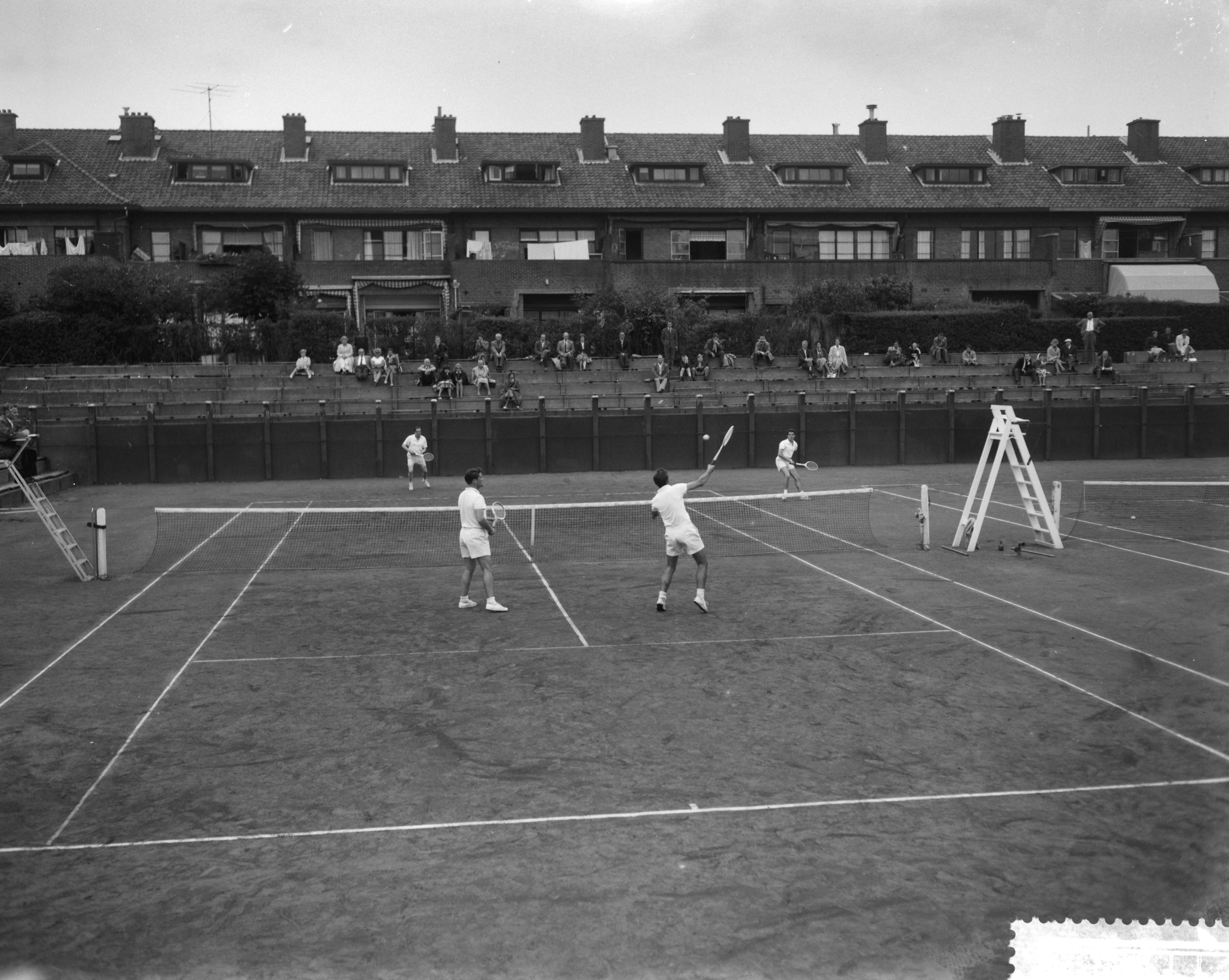 Fotocollectie Anefo — Nationale tenniskampioenschappen op de METS-banen te Scheveningen. Kwartfinale partij Herendubbel — Foto: Bilsen, Joop van / Anefo. Licentie: Set B: Rechtenvrij / Publiek Domein. Bron: Nationaal Archief. http://hdl.handle.net/10648/a9b6d706-d0b4-102d-bcf8-003048976d84