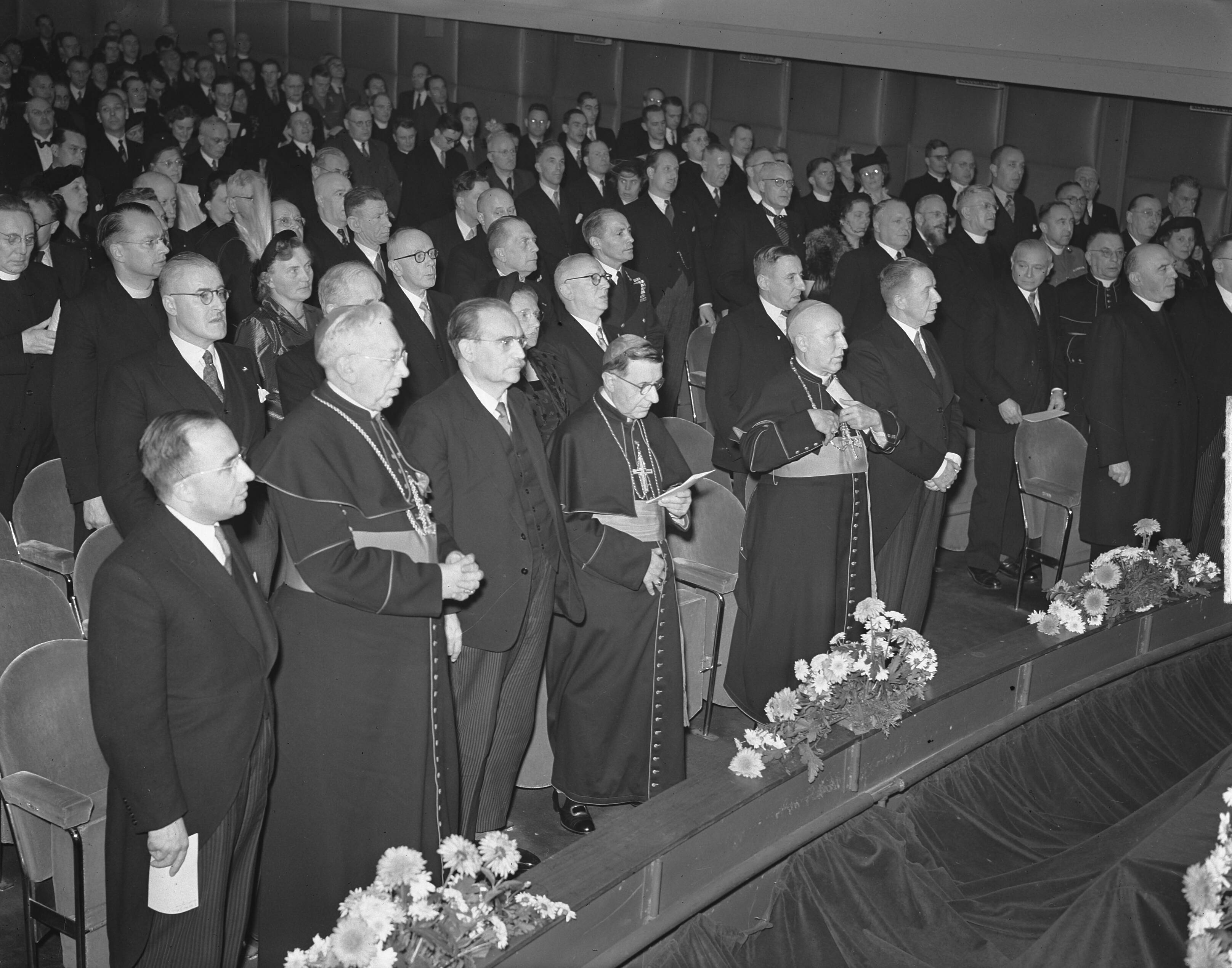 KRO 25-jarig jubileum — KRO 25-jarig jubileum. Op de eerste rij vlnr. staatssecretaris Cals, mgr. Huibers, bisschop van Haarlem, minister-president Drees, pauselijk nuntius mgr. Giobbe, mgr. Mutsaerts, bisschop van 's-Hertogenbosc, minister Rutten en prof. Kors, voorzitter KRO — Foto: Bilsen, Joop van / Anefo. Licentie: Set B: Rechtenvrij / Publiek Domein. Bron: Nationaal Archief. http://hdl.handle.net/10648/a8e262c8-d0b4-102d-bcf8-003048976d84