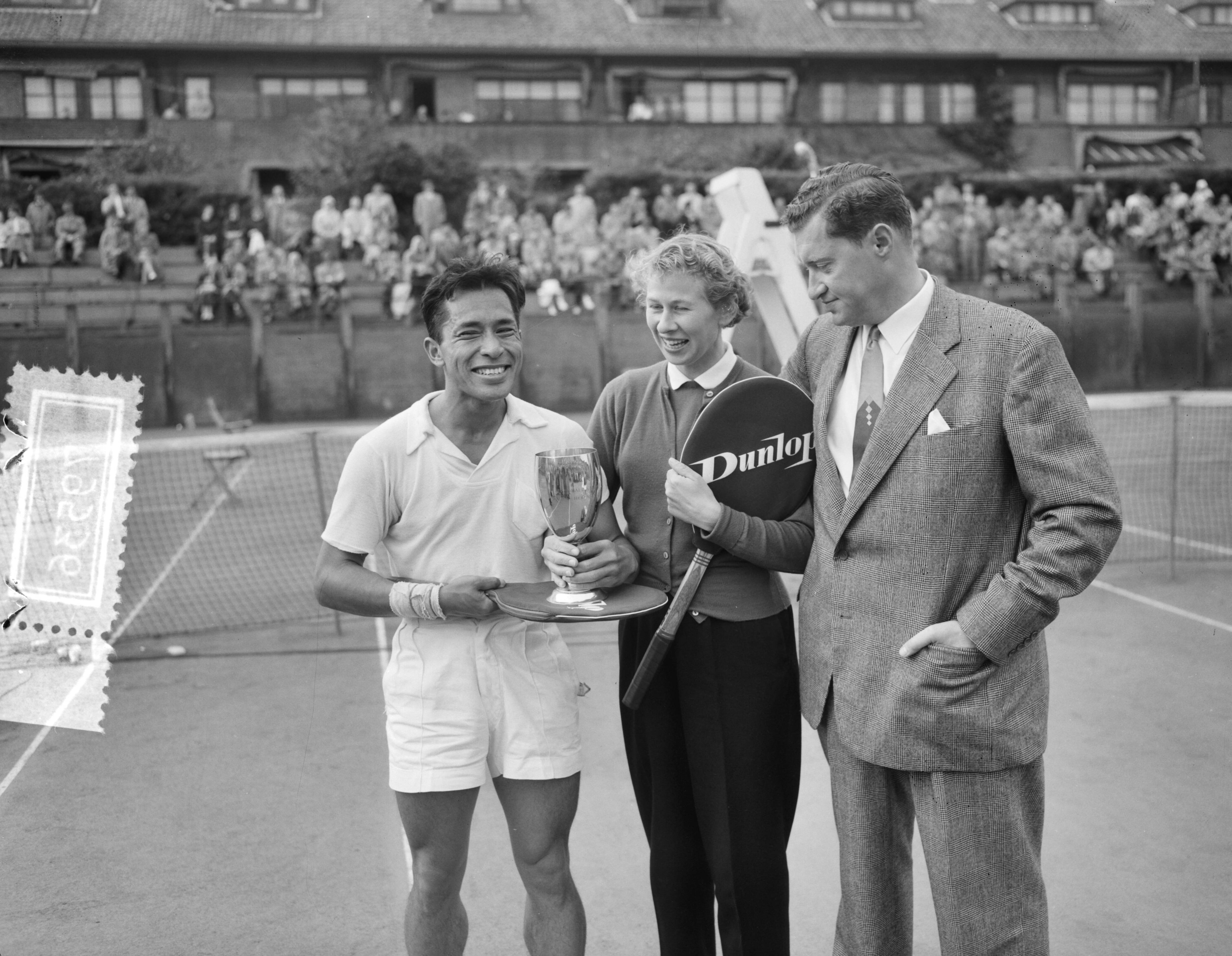Fotocollectie Anefo — Nederlandse tenniskampioenschappen op de METS-banen. Winnaars heren en dames enkelspel Lex Karamoy en Jopie Roos-van de Wal. Rechts KNLTB voorzitter Huib Wilton — Foto: Fotograaf Onbekend / Anefo. Licentie: Set B: Rechtenvrij / Publiek Domein. Bron: Nationaal Archief. http://hdl.handle.net/10648/ad77d17e-d0b4-102d-bcf8-003048976d84