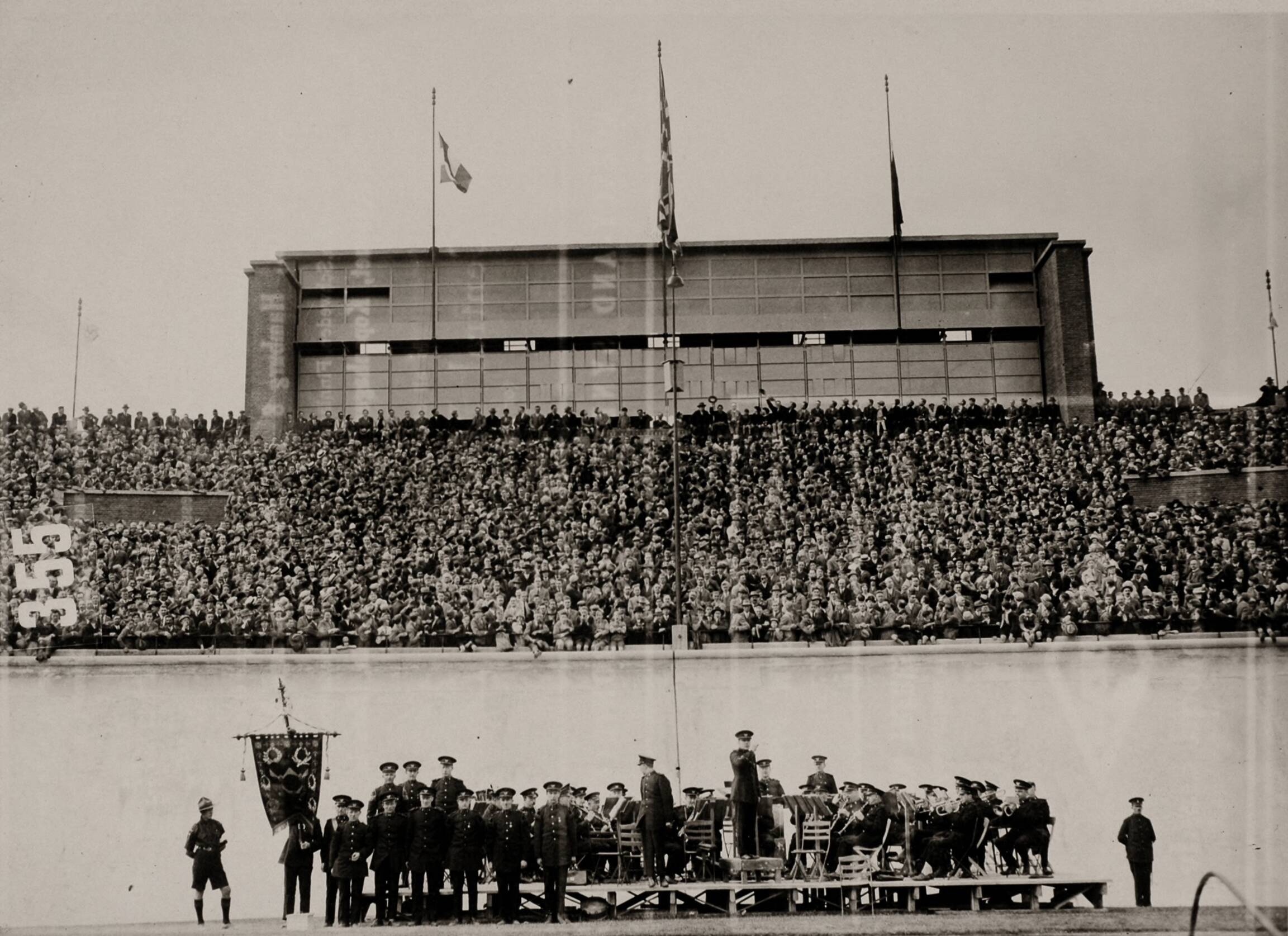 Cultuur, Sport — Sport. Olympische Spelen 1928 Amsterdam, Nederland : Toeschouwers op de volle tribune van het olympisch stadion tijdens een ceremonie na een olympische discipline. Vooraan speelt een muziekcorps. — Foto: Fotograaf Onbekend / Algemeen Fotobureau Amsterdam / Spaarnestad Photo (05887). Licentie: Set B: Rechtenvrij / Publiek Domein. Bron: Nationaal Archief. http://hdl.handle.net/10648/35429da6-d58e-a382-e063-6df0900a6686