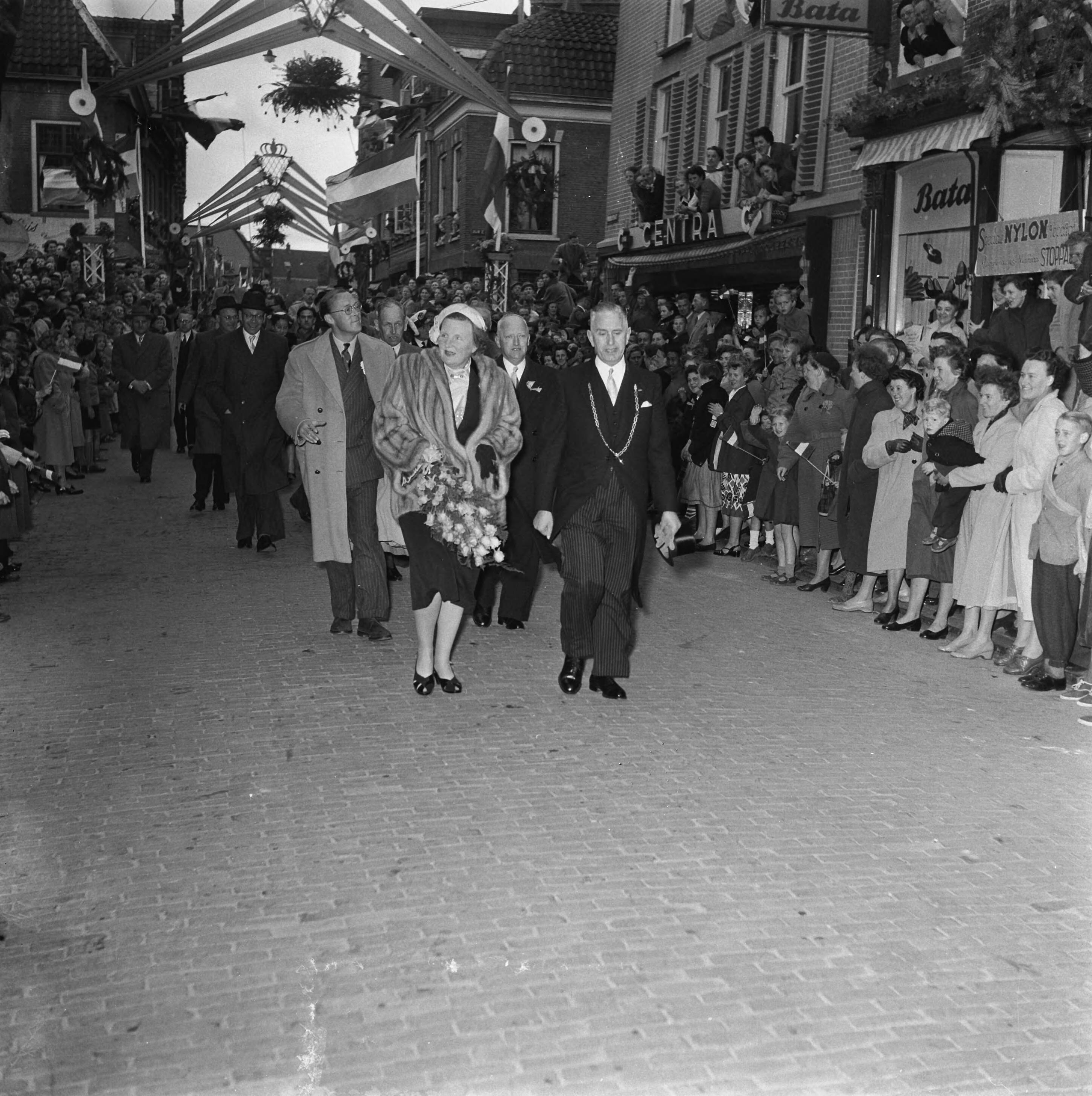 Koninklijk bezoek aan 15 gemeentes in Zuid-Holland (Rijnstreek en Merengebied) — Koningin Julina en prins Bernhard tijdens hun bezoek aan Woerden. Zij lopen met burgemeester H.H.C. Vos door de Voorstraat — Foto: Noske, J.D. / Anefo. Licentie: Set B: Rechtenvrij / Publiek Domein. Bron: Nationaal Archief. http://hdl.handle.net/10648/a9222f7a-d0b4-102d-bcf8-003048976d84