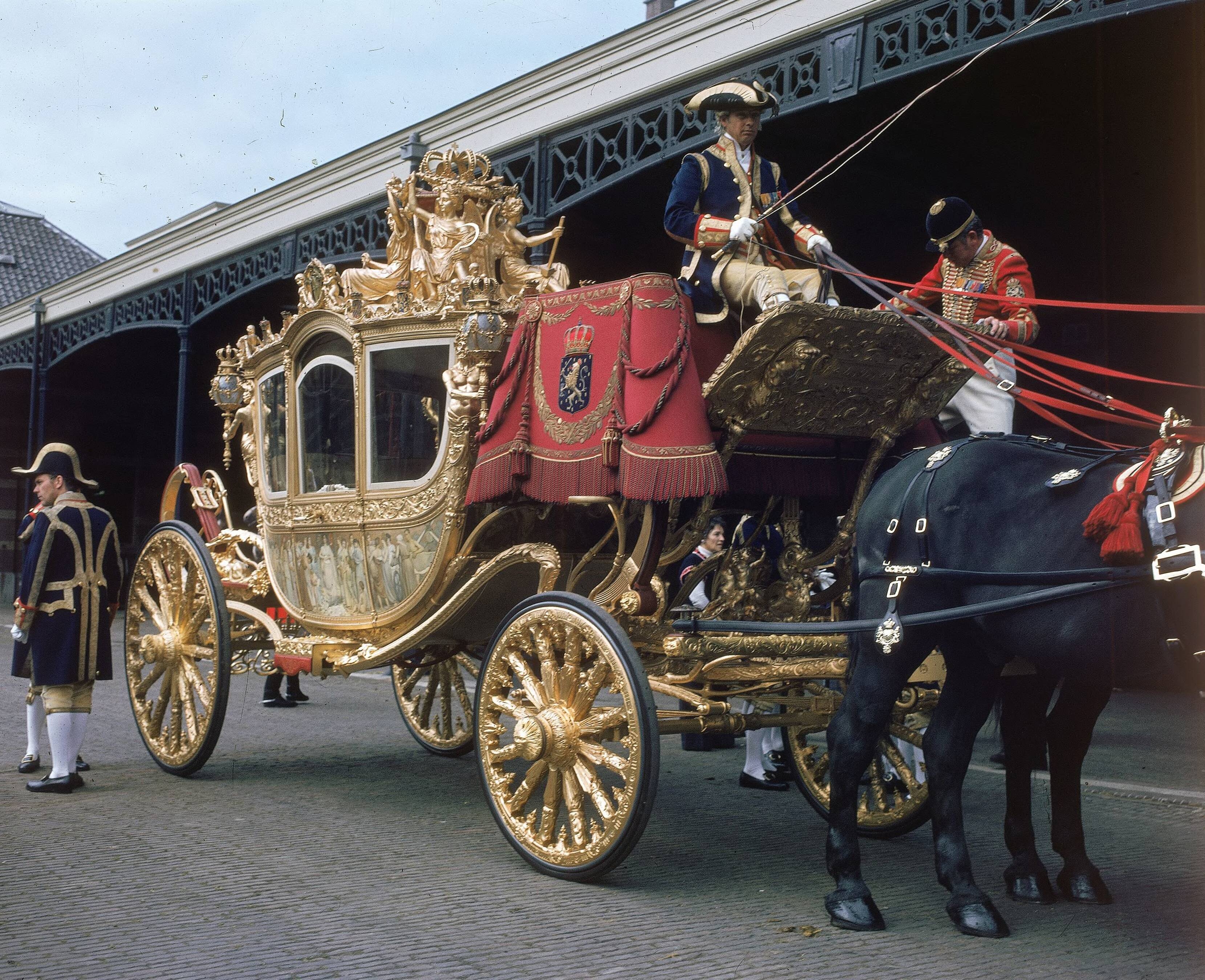 Fotocollectie RVD / Koninklijk Huis — Prinsjesdag - Gouden koets, met koetsier, lakei, stalpersoneel en paard op de binnenplaats van de koninklijke stallen aan de Noordwal te Den Haag — Foto: Mastenbroek, Cees / RVD. Licentie: Set B: Rechtenvrij / Publiek Domein. Bron: Nationaal Archief. http://hdl.handle.net/10648/afb2711a-d0b4-102d-bcf8-003048976d84