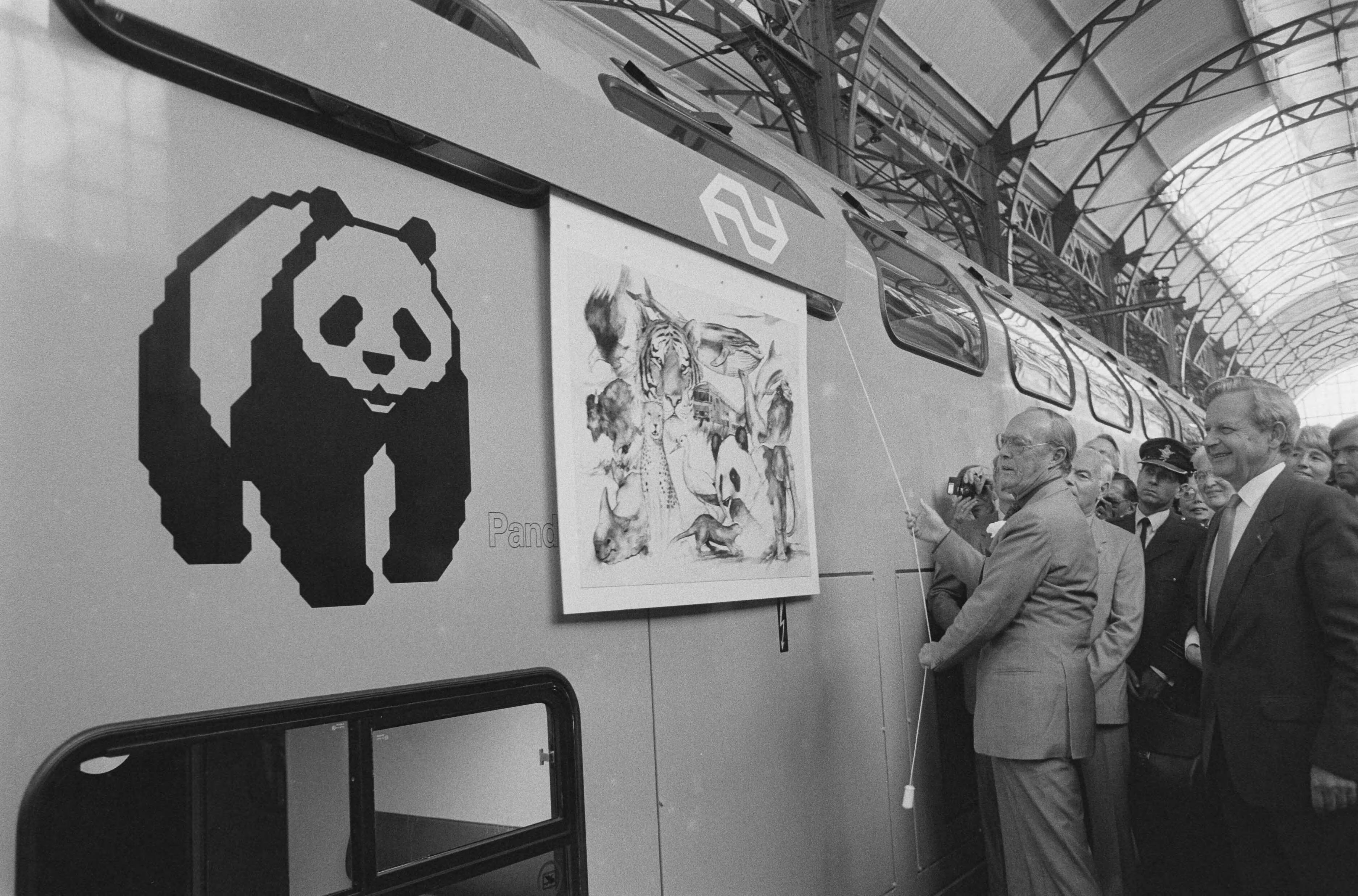 Fotocollectie Anefo — Prins Bernhard vernoemt op Station Hollands Spoor in Den Haag eerste NS-dubbeldekker tot Panda; rechts: NS directeur Ploeger — Foto: Croes, Rob C. / Anefo. Licentie: Set B: Rechtenvrij / Publiek Domein. Bron: Nationaal Archief. http://hdl.handle.net/10648/ad586cd0-d0b4-102d-bcf8-003048976d84