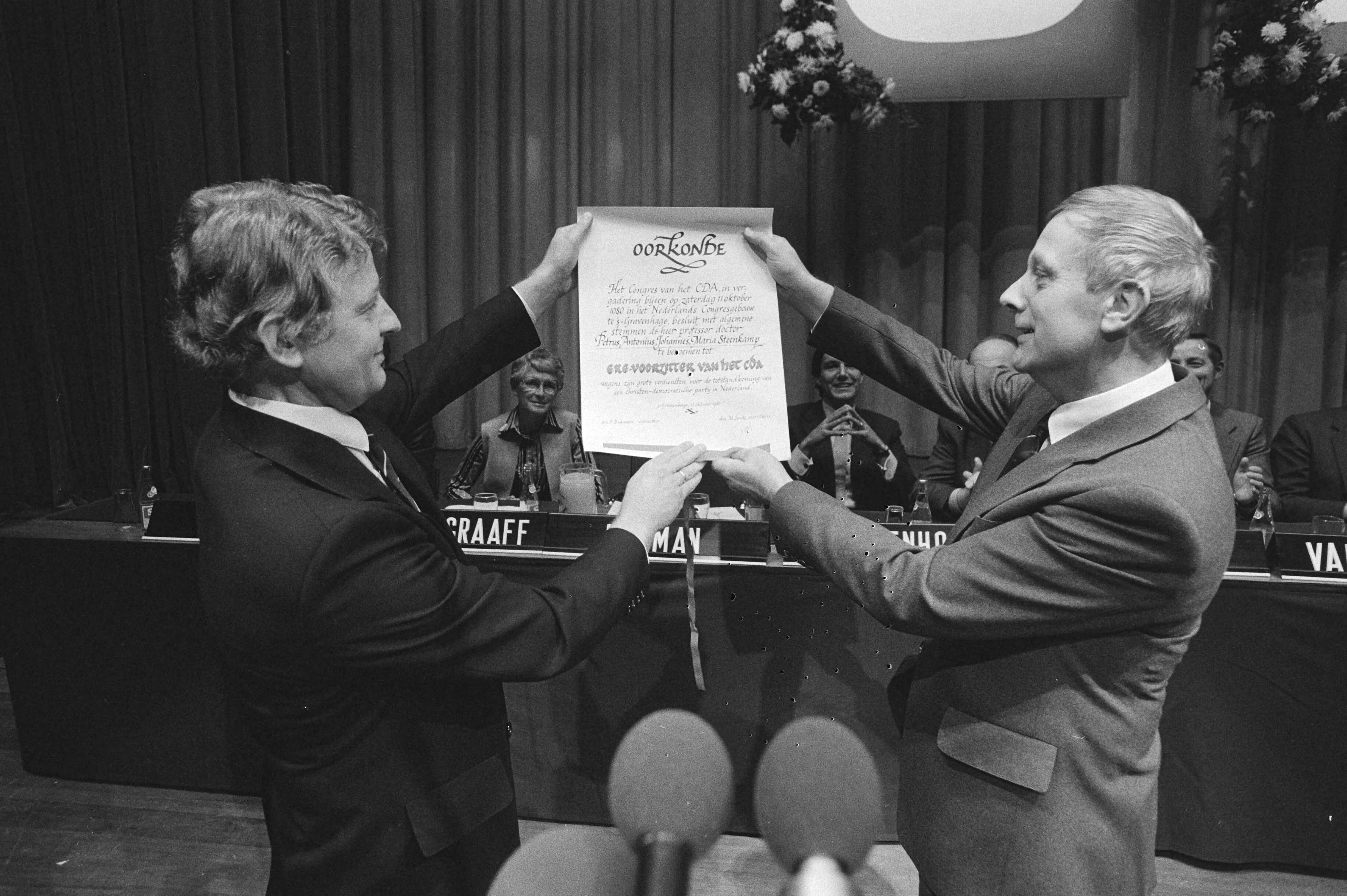 Fotocollectie Anefo — Fusie congres CDA in Den Haag , Steenkamp ere-voorzitter CDA, Bukman (l) gaf Steenkamp ere-oorkonde — Foto: Antonisse, Marcel / Anefo. Licentie: Set B: Rechtenvrij / Publiek Domein. Bron: Nationaal Archief. http://hdl.handle.net/10648/acea9962-d0b4-102d-bcf8-003048976d84