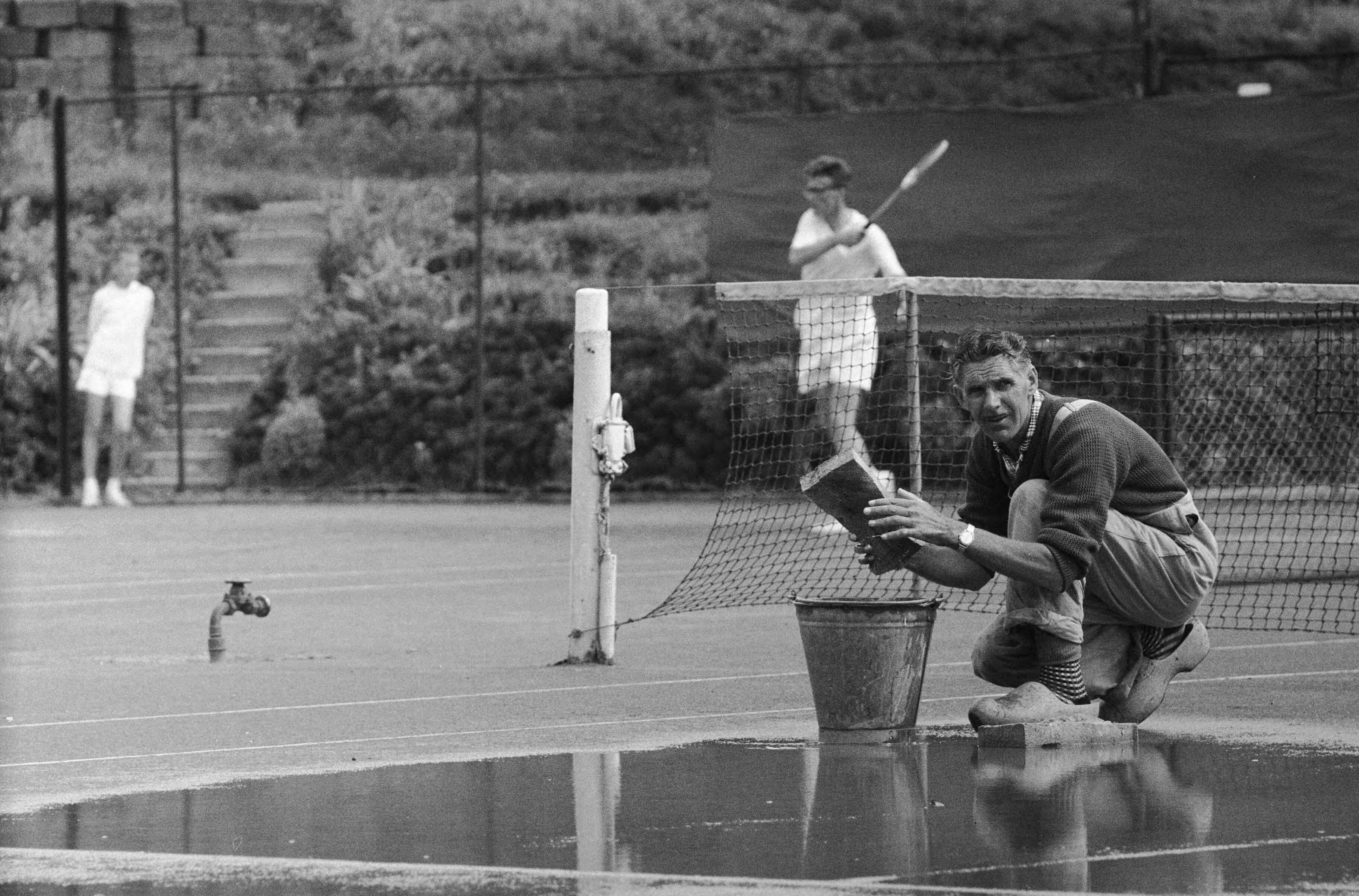 Fotocollectie Anefo — Nederlandse tenniskampioenschappen op de METS-banen te Scheveningen. Baan 2 wordt met dweilen drooggemaakt — Foto: Pot, Harry / Anefo. Licentie: Set B: Rechtenvrij / Publiek Domein. Bron: Nationaal Archief. http://hdl.handle.net/10648/a9b6a4fc-d0b4-102d-bcf8-003048976d84