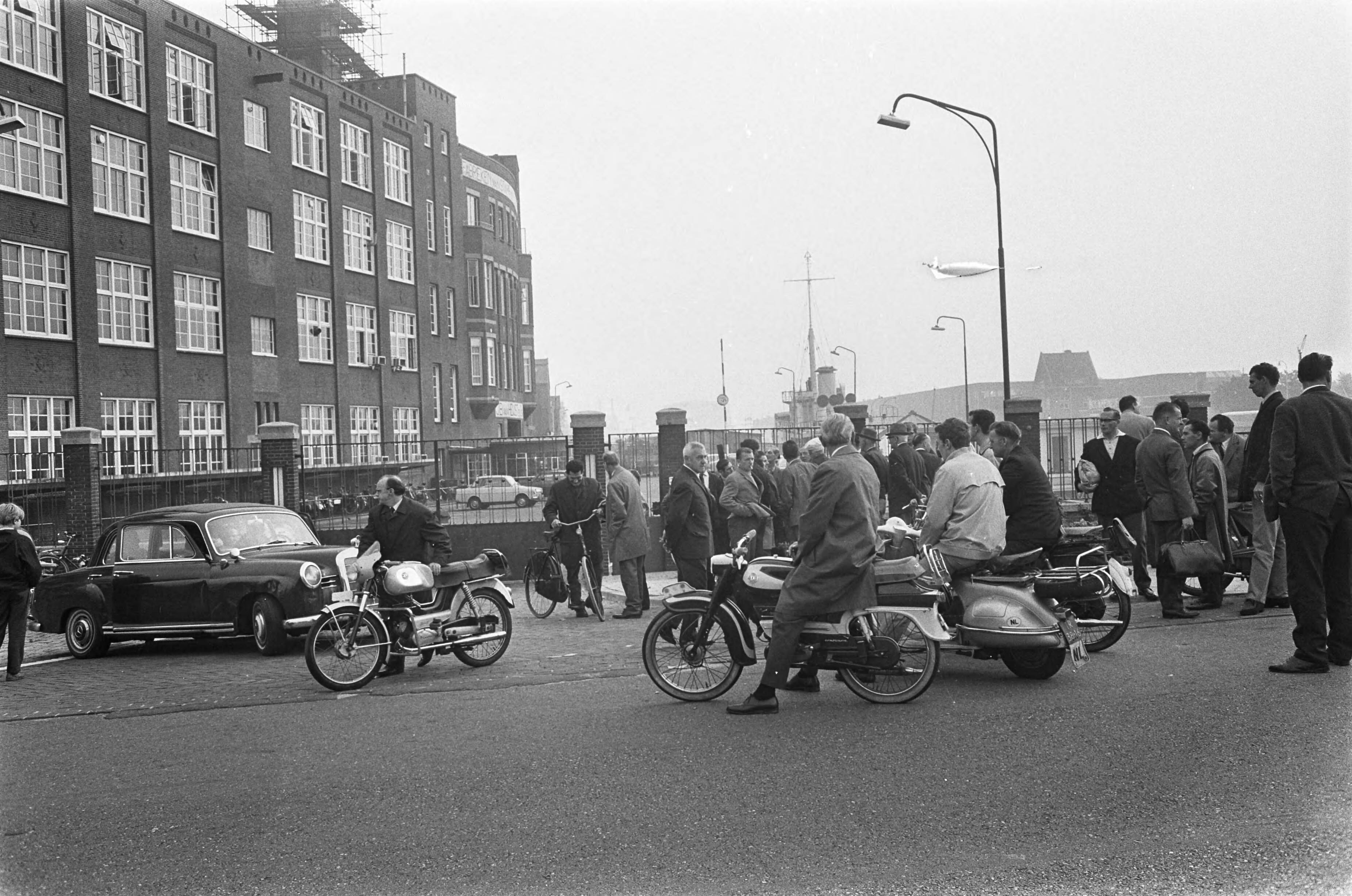 Fotocollectie Anefo — Van Heijst te Den Haag . Ontslagen arbeiders voor de poort — Foto: Koch, Eric / Anefo. Licentie: Set B: Rechtenvrij / Publiek Domein. Bron: Nationaal Archief. http://hdl.handle.net/10648/ab27b402-d0b4-102d-bcf8-003048976d84
