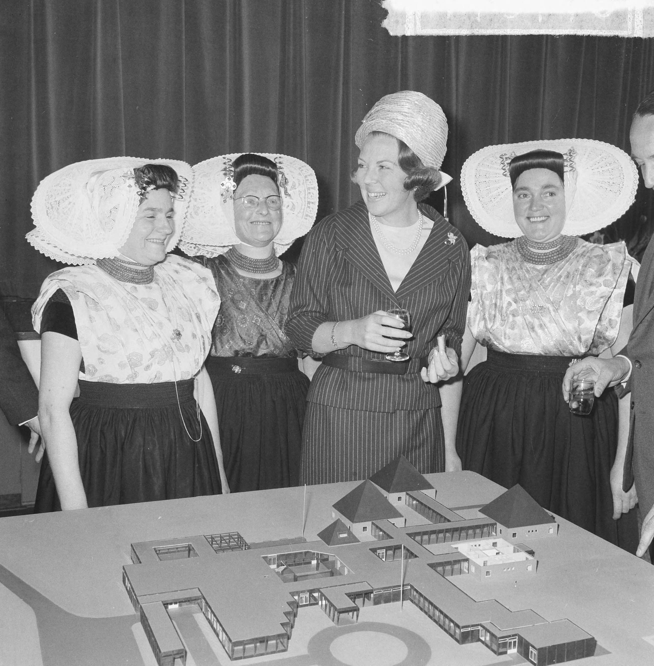 Fotocollectie Anefo — Prinses Beatrix was aanwezig bij de eerste steenlegging voor het jongerenontmoetingscentrum "Het Zilveren Schor" nabij Arnemuiden, prinses Beatrix tussen dames in klederdracht. Voor haar de maquette van het gebouw, een ontwerp van architect Onno Greiner — Foto: Nijs, Jac. de / Anefo. Licentie: Set B: Rechtenvrij / Publiek Domein. Bron: Nationaal Archief. http://hdl.handle.net/10648/aaa1bc44-d0b4-102d-bcf8-003048976d84