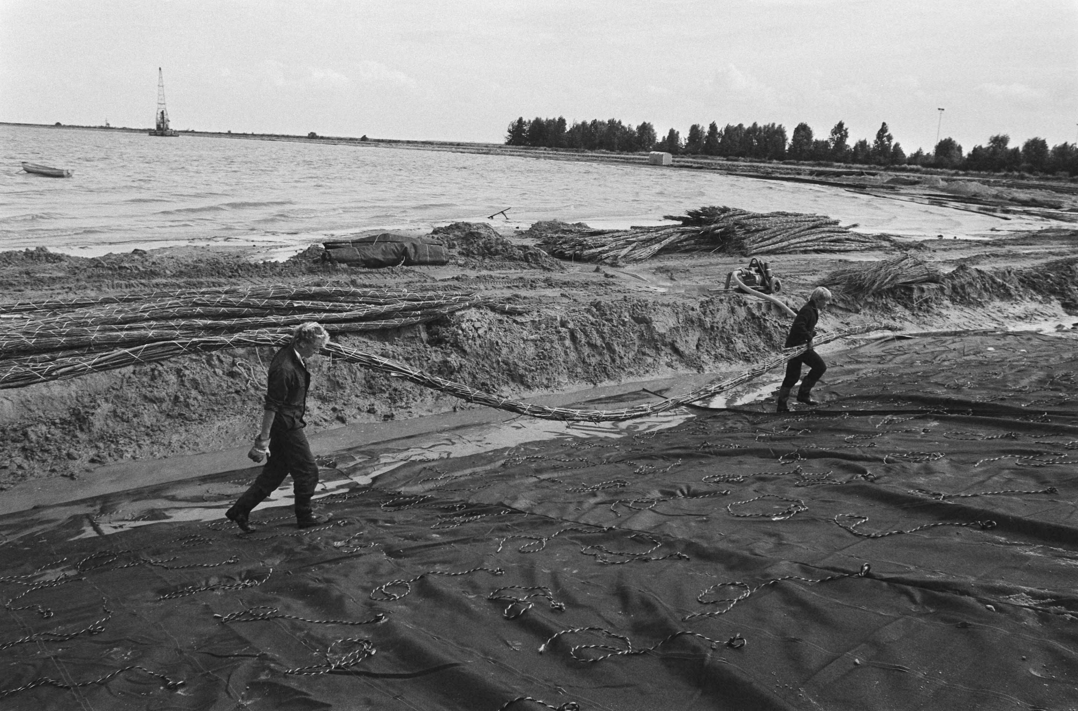 Fotocollectie Anefo — Aanleg nieuwe dijk bij voormalig eiland Marken; aanbrengen bundel wilgenhout op kunststof van de dijk — Foto: Bogaerts, Rob / Anefo. Licentie: Set B: Rechtenvrij / Publiek Domein. Bron: Nationaal Archief. http://hdl.handle.net/10648/ad563a00-d0b4-102d-bcf8-003048976d84