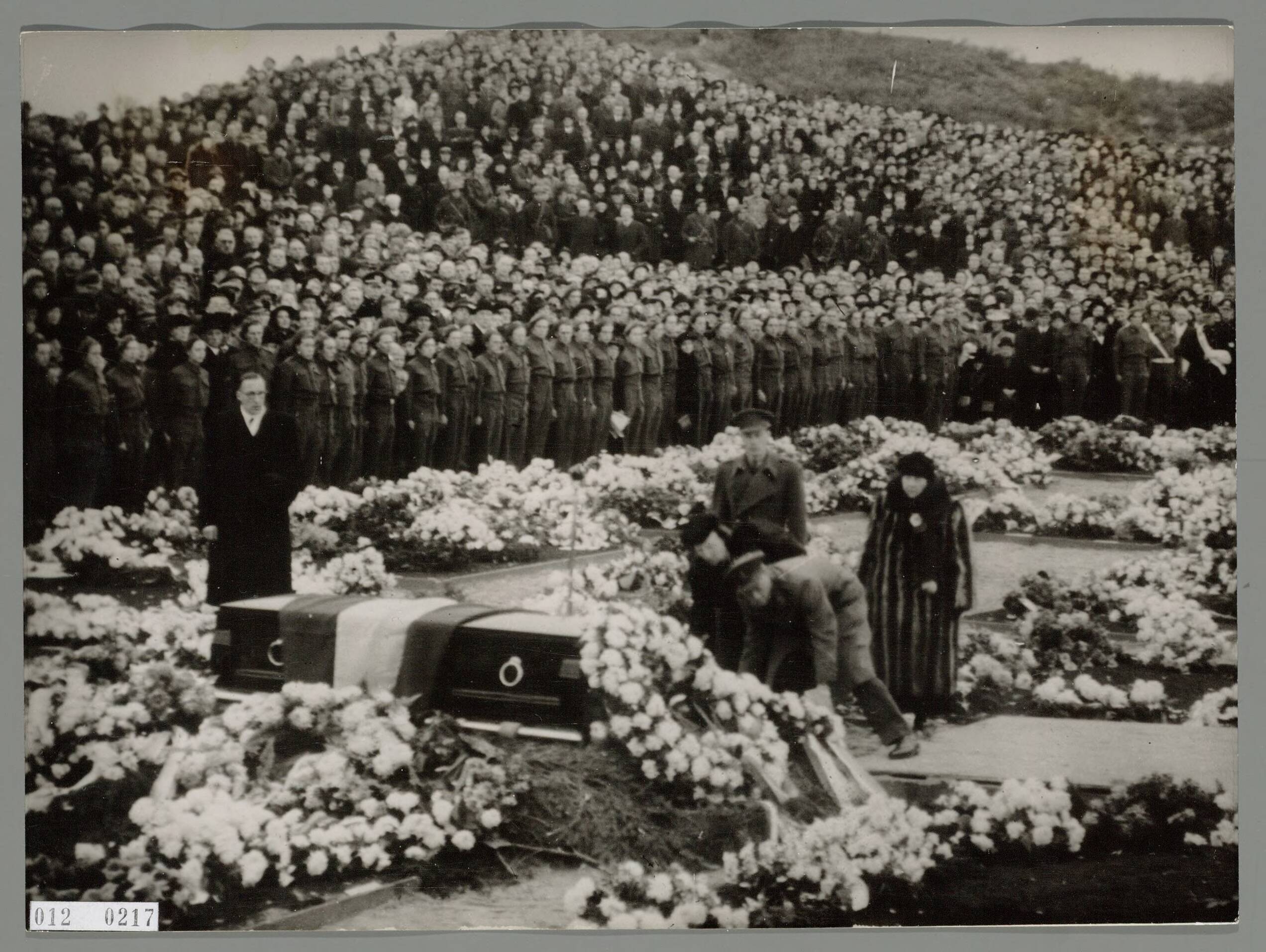 Fotocollectie RVD / Koninklijk Huis — Prins Bernhard en prinses Juliana leggen een krans op de kist bij de herbegrafenisceremonie te Haarlem van de 400 Nederlandse slachtoffers. Koningin Wilhelmina kijkt toe — Foto: Onbekend / RVD. Licentie: Set B: Rechtenvrij / Publiek Domein. Bron: Nationaal Archief. http://hdl.handle.net/10648/afab32c4-d0b4-102d-bcf8-003048976d84