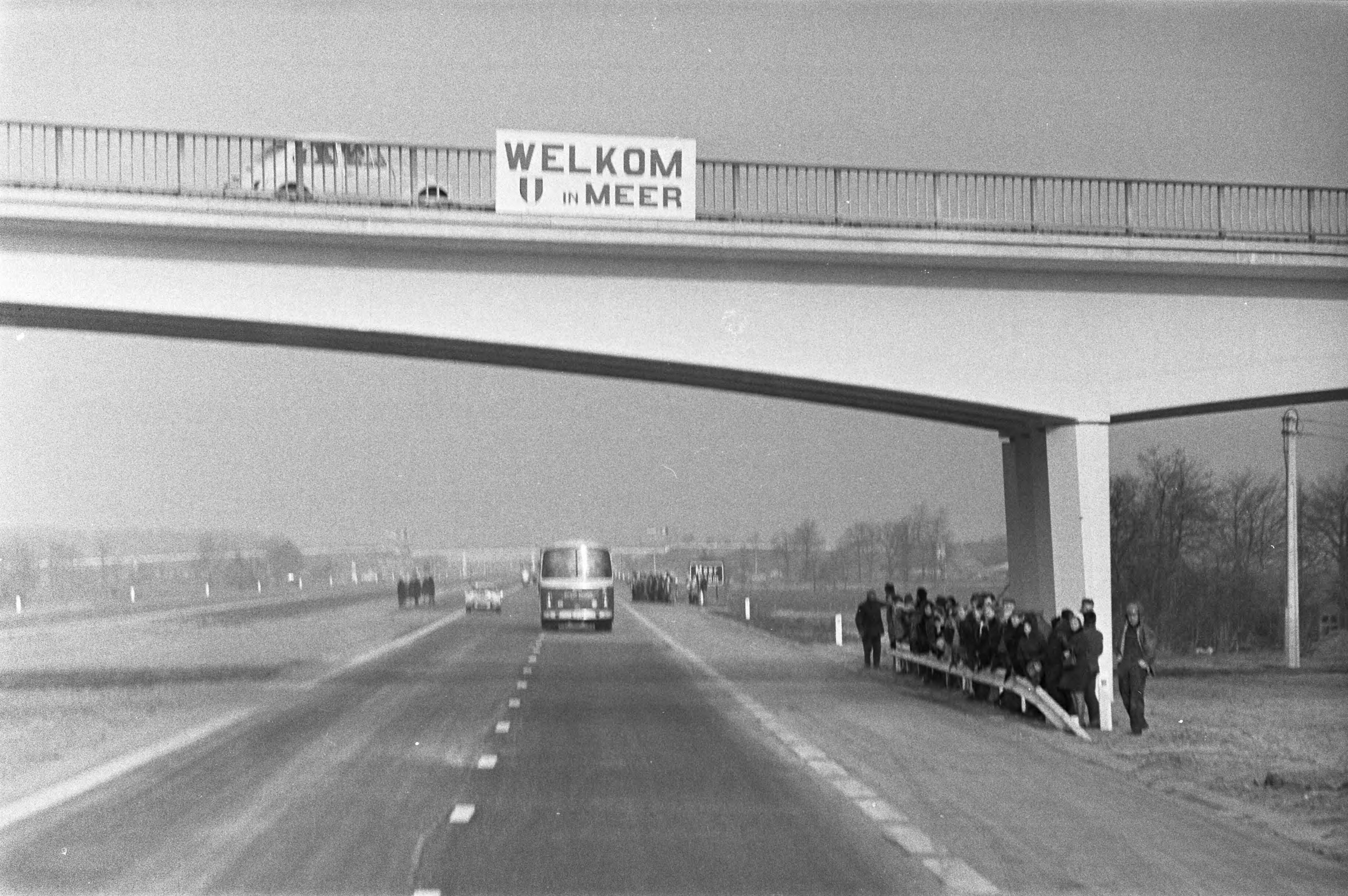 Opening van de E10, de nieuwe snelweg tussen Breda en Antwerpen, door — De bus met daarin koningin Juliana en koning Boudewijn op de nieuwe weg — Foto: Fotograaf Onbekend / Anefo. Licentie: Set B: Rechtenvrij / Publiek Domein. Bron: Nationaal Archief. http://hdl.handle.net/10648/abde5752-d0b4-102d-bcf8-003048976d84