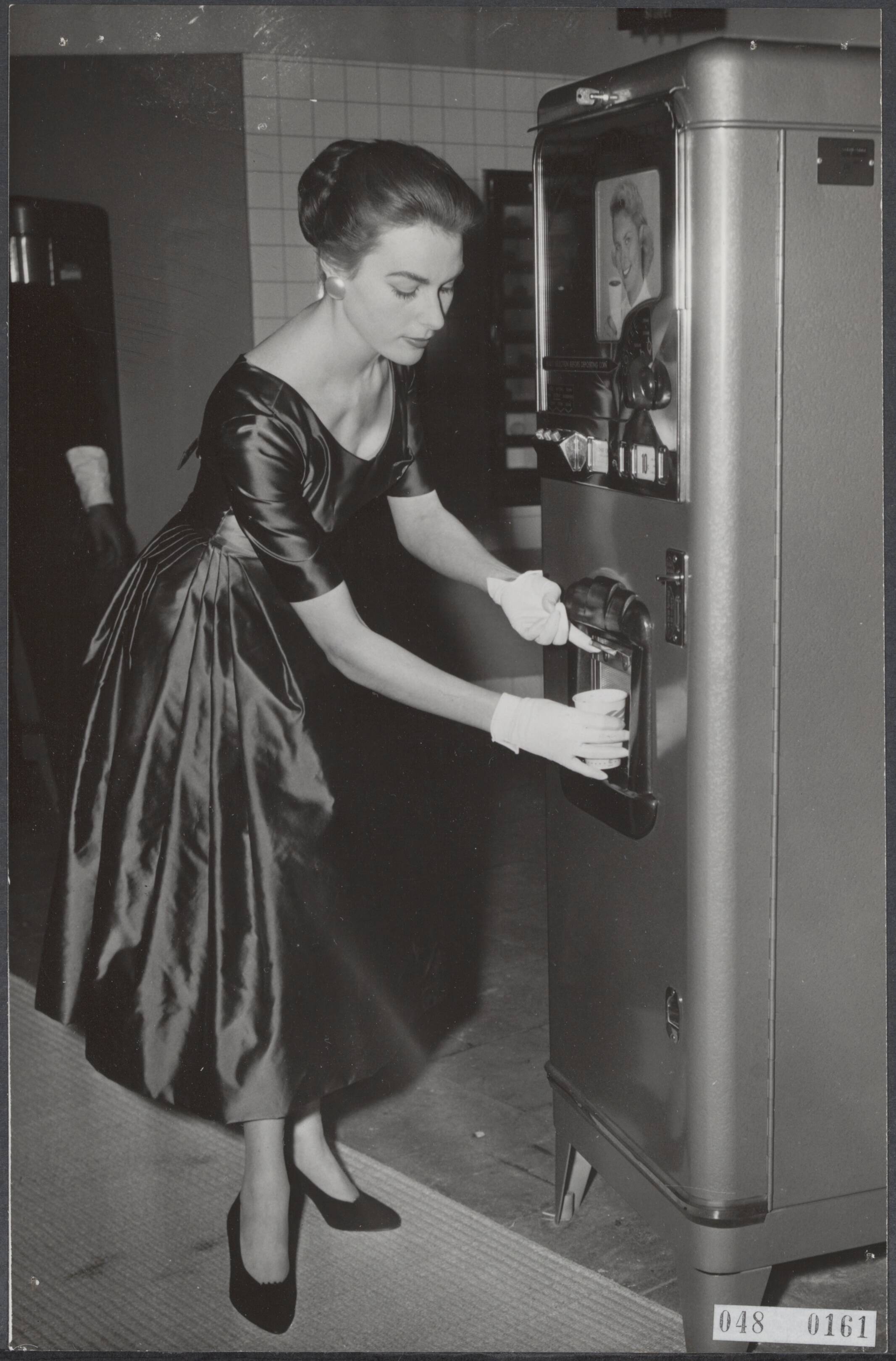 Fotocollectie Elsevier Binnenland — Nieuwe op de Najaarsbeurs in Utrecht. Een koffie-automaat verzorgt uw koffie, zonder dat een kelner hiervoor nodig is. Door het inwerpen van een penning, waarvoor nog geen prijs werd vastgesteld, ontvangt men een beker koffie — Foto: Fotograaf Onbekend / Anefo. Licentie: Set B: Rechtenvrij / Publiek Domein. Bron: Nationaal Archief. http://hdl.handle.net/10648/ae00f198-d0b4-102d-bcf8-003048976d84