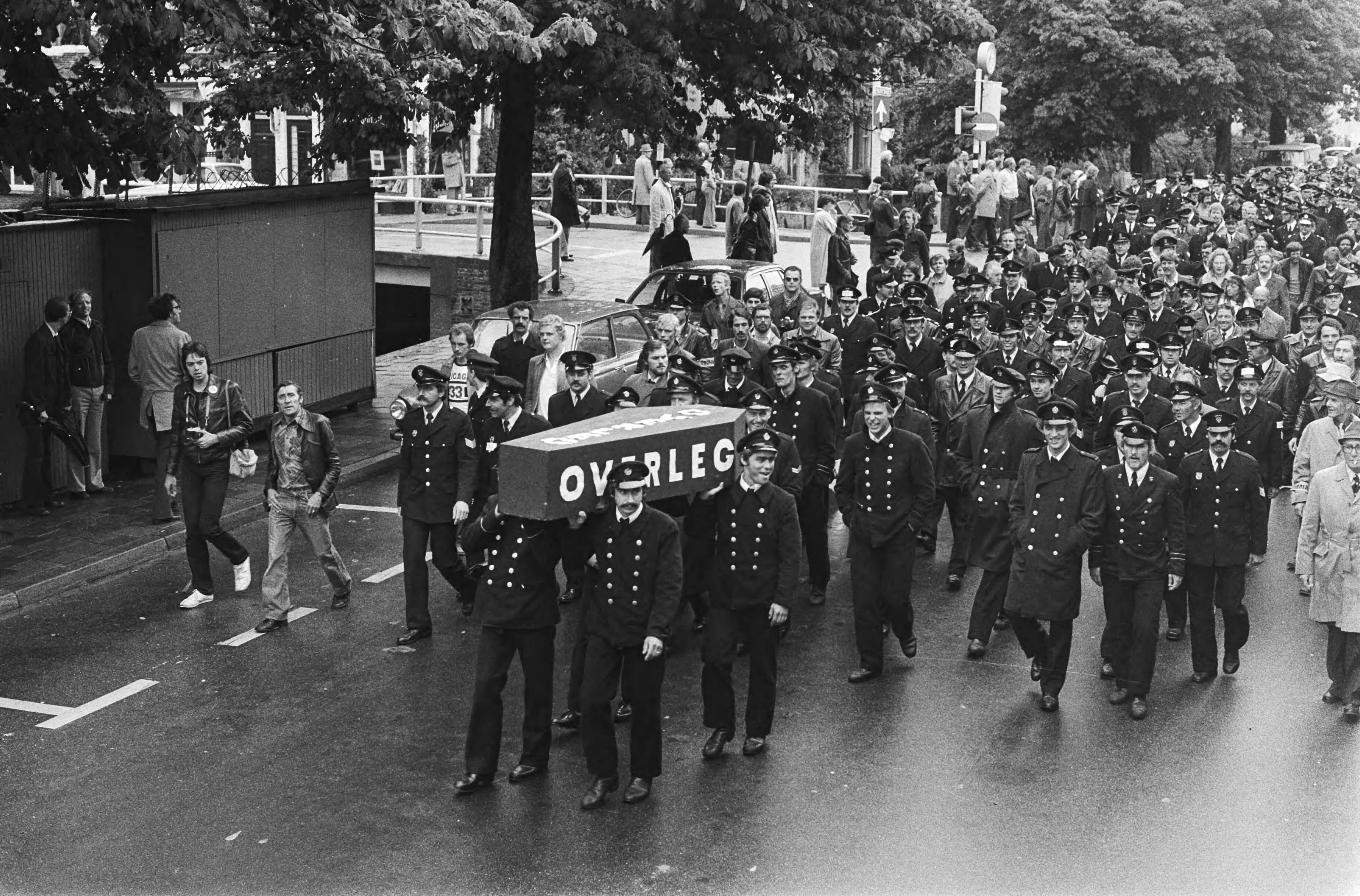 Fotocollectie Anefo — Ambtenarendemonstratie, Den Haag tegen bezuigingsplannen Van Agt ; brandweermannen met doodskist — Foto: Peters, Hans / Anefo. Licentie: Set B: Rechtenvrij / Publiek Domein. Bron: Nationaal Archief. http://hdl.handle.net/10648/acb77780-d0b4-102d-bcf8-003048976d84