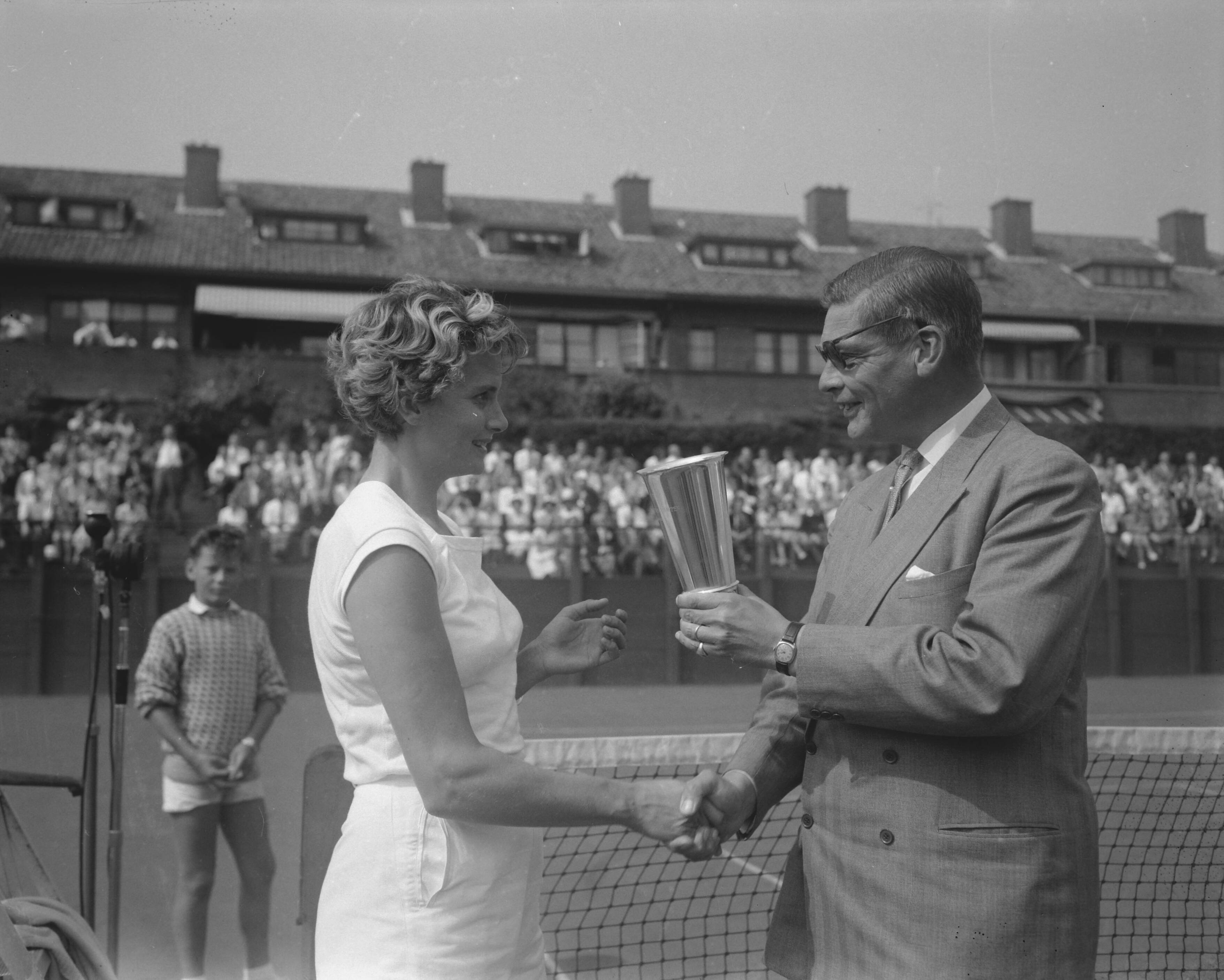 Fotocollectie Anefo — Nederlandse tenniskampioenschappen op de METS-banen te Scheveningen. mr. E.H. Muntz , voorzitter van de Koninklijke Nederlandse Lawntennis Bond reikt de beker uit aan de winnares van het damesenkel, Fenny de Soet-ten Bosch — Foto: Bilsen, Joop van / Anefo. Licentie: Set B: Rechtenvrij / Publiek Domein. Bron: Nationaal Archief. http://hdl.handle.net/10648/a982b084-d0b4-102d-bcf8-003048976d84