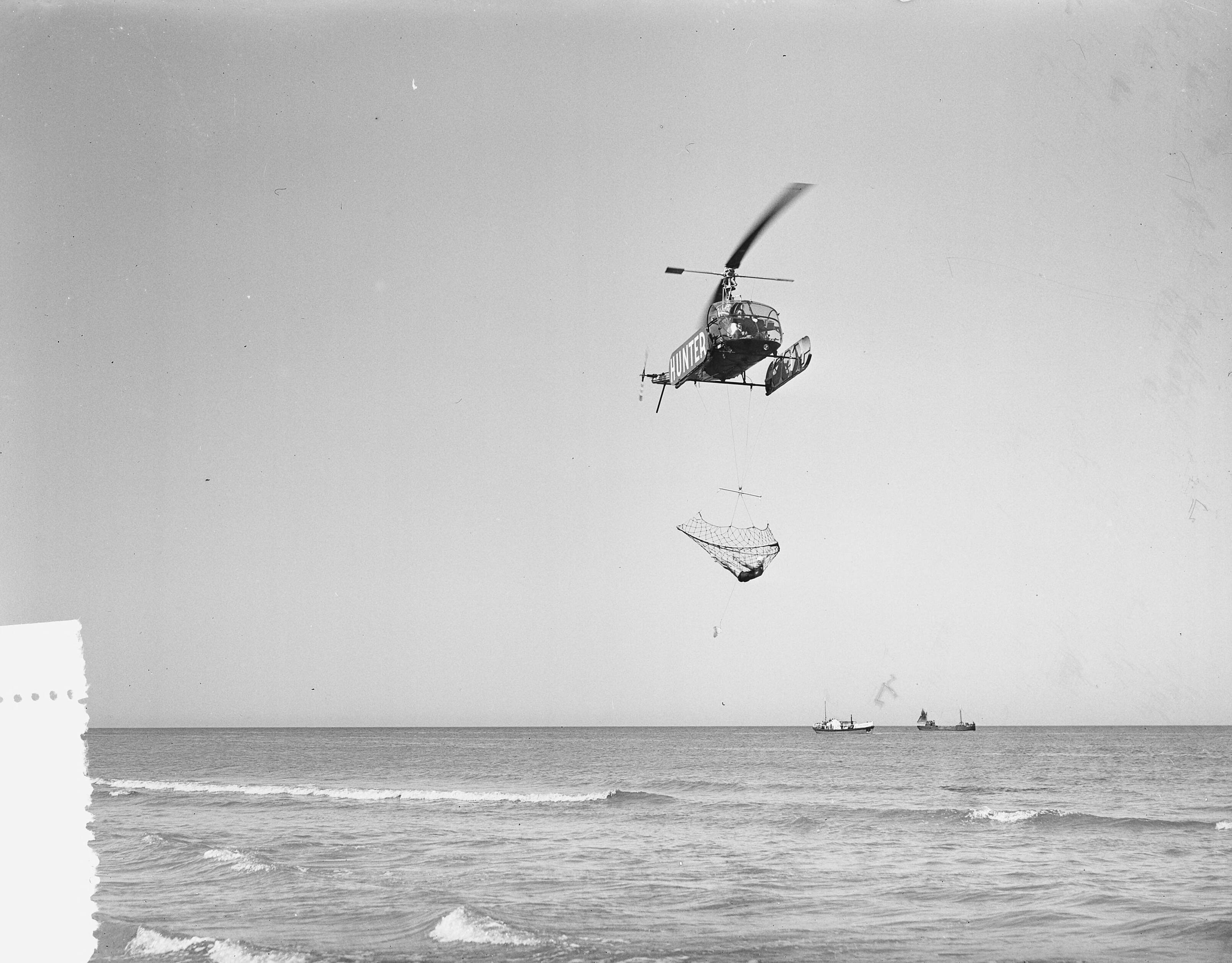 Fotocollectie Anefo — Demonstratie helicopter van Aero Ypenburg met nieuw reddingsnet bij het strand van Scheveningen. In het net bevind zich de 14-jarige "drenkelinge" Marie-Antoinette Verlinden — Foto: Bilsen, Joop van / Anefo. Licentie: Set B: Rechtenvrij / Publiek Domein. Bron: Nationaal Archief. http://hdl.handle.net/10648/a939fc2c-d0b4-102d-bcf8-003048976d84
