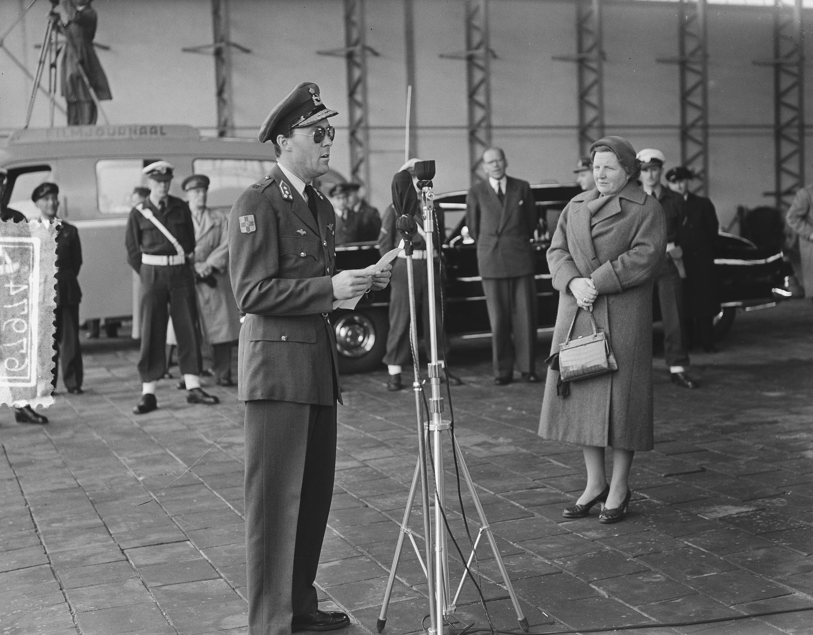 Prins Bernhard arriveert op Soesterberg na een reis naar Zuid-Afrika — Aankomst prins Bernhard op Soesterberg uit Zuid Afrika. Prins Bernhard achter de microfoon, rechts koningin Juliana — Foto: Bilsen, Joop van / Anefo. Licentie: Set B: Rechtenvrij / Publiek Domein. Bron: Nationaal Archief. http://hdl.handle.net/10648/a92ba9f6-d0b4-102d-bcf8-003048976d84