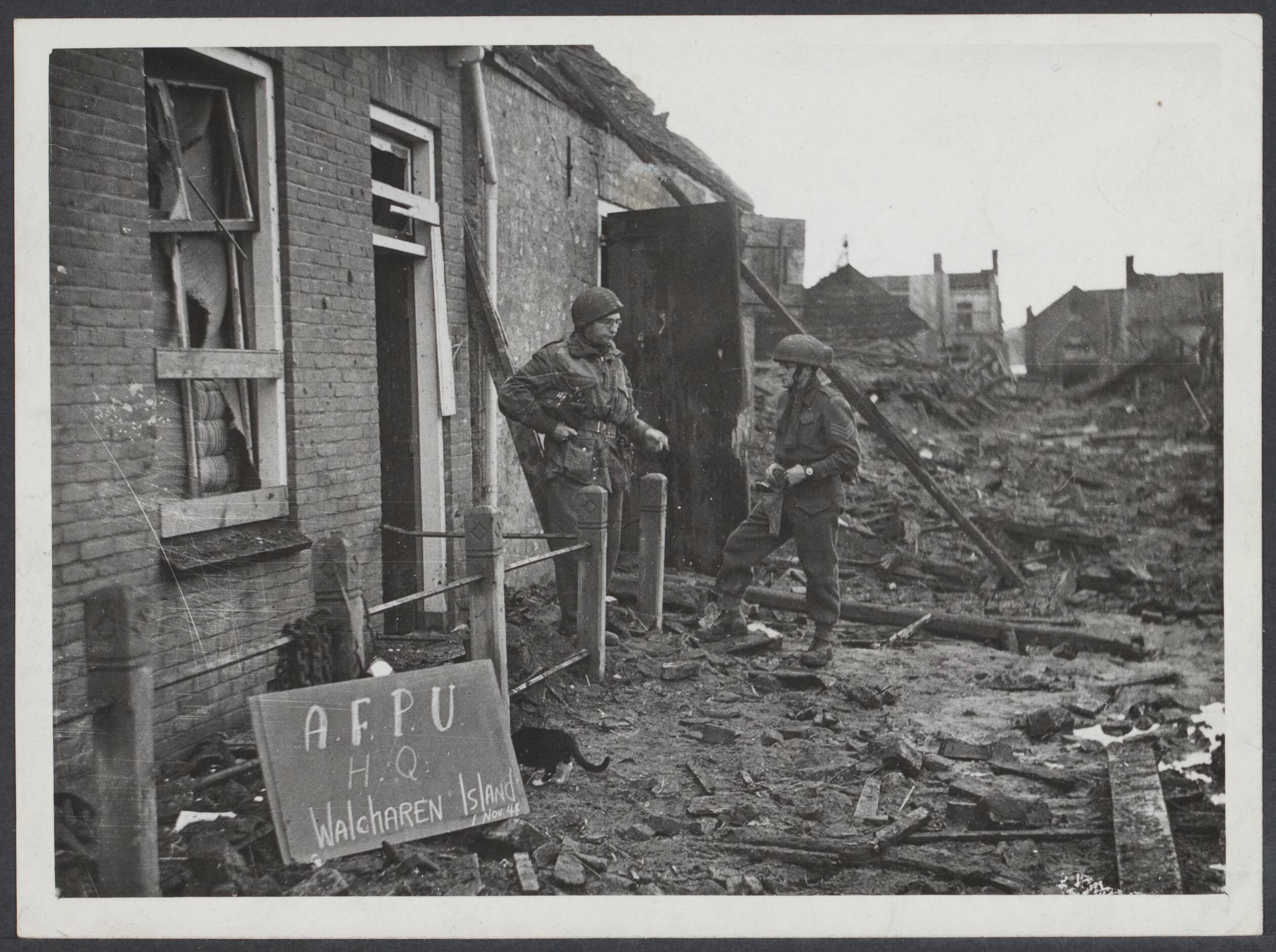 Westkapelle. Raid op de wijk van - 1944 — Invasion of Walcheren Island. The Army Film and Photo Unit H.Q. on Walcheren island. Sergeant Crocker of the A.R.P.U. and sergeant Dangen of the Canadian Forces are seen outside theri dwelling — Foto: War Office. Licentie: Set B: Rechtenvrij / Publiek Domein. Bron: Nationaal Archief. http://hdl.handle.net/10648/eb349c67-101b-b6b4-975a-2e24caa54a1f