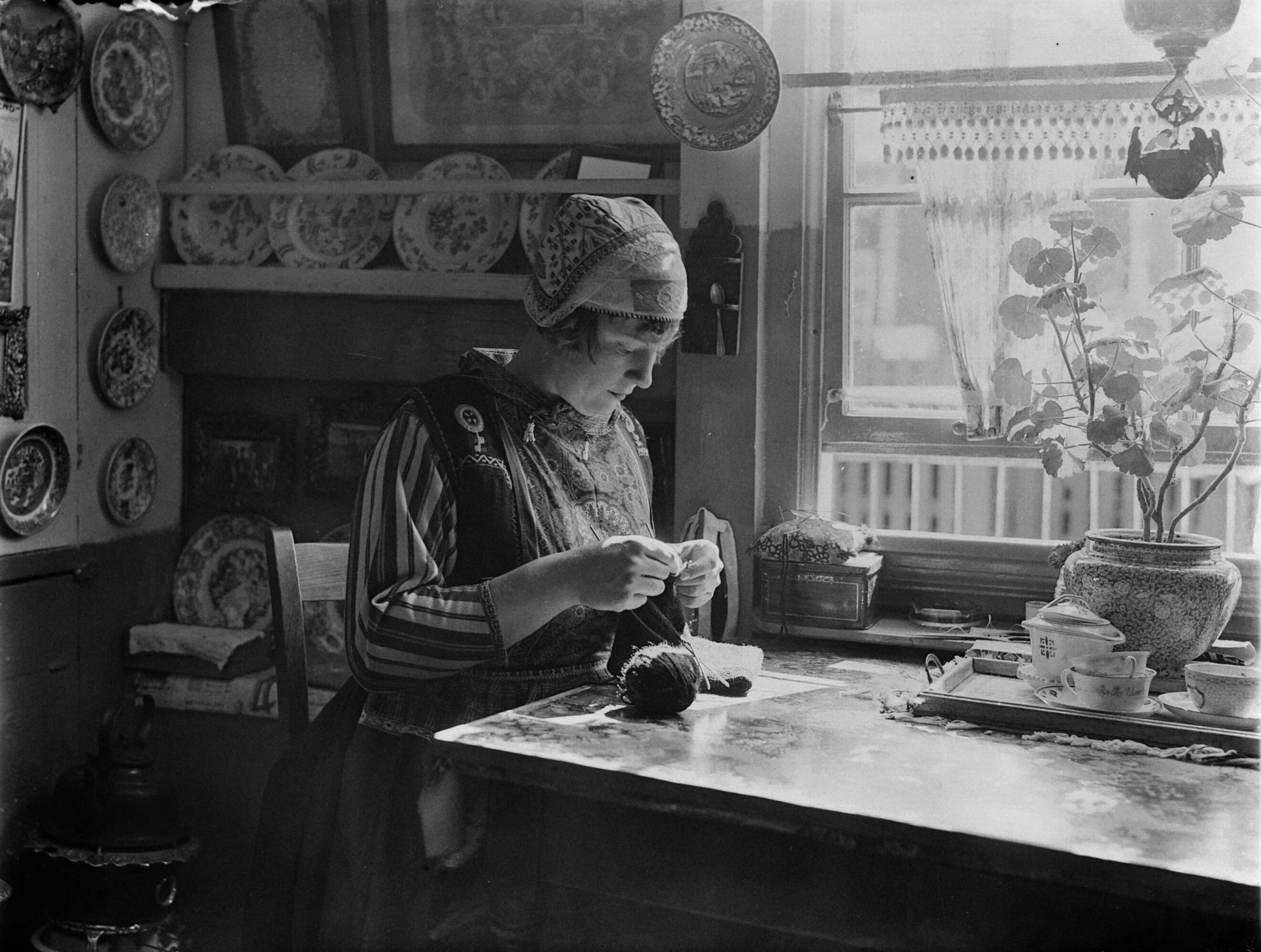 Klederdrachten in Nederland — Breiende vrouw in Marker klederdracht in een Marker interieur — Foto: Poll, Willem van de. Licentie: Set B: Rechtenvrij / Publiek Domein. Bron: Nationaal Archief. http://hdl.handle.net/10648/aea7aba0-d0b4-102d-bcf8-003048976d84