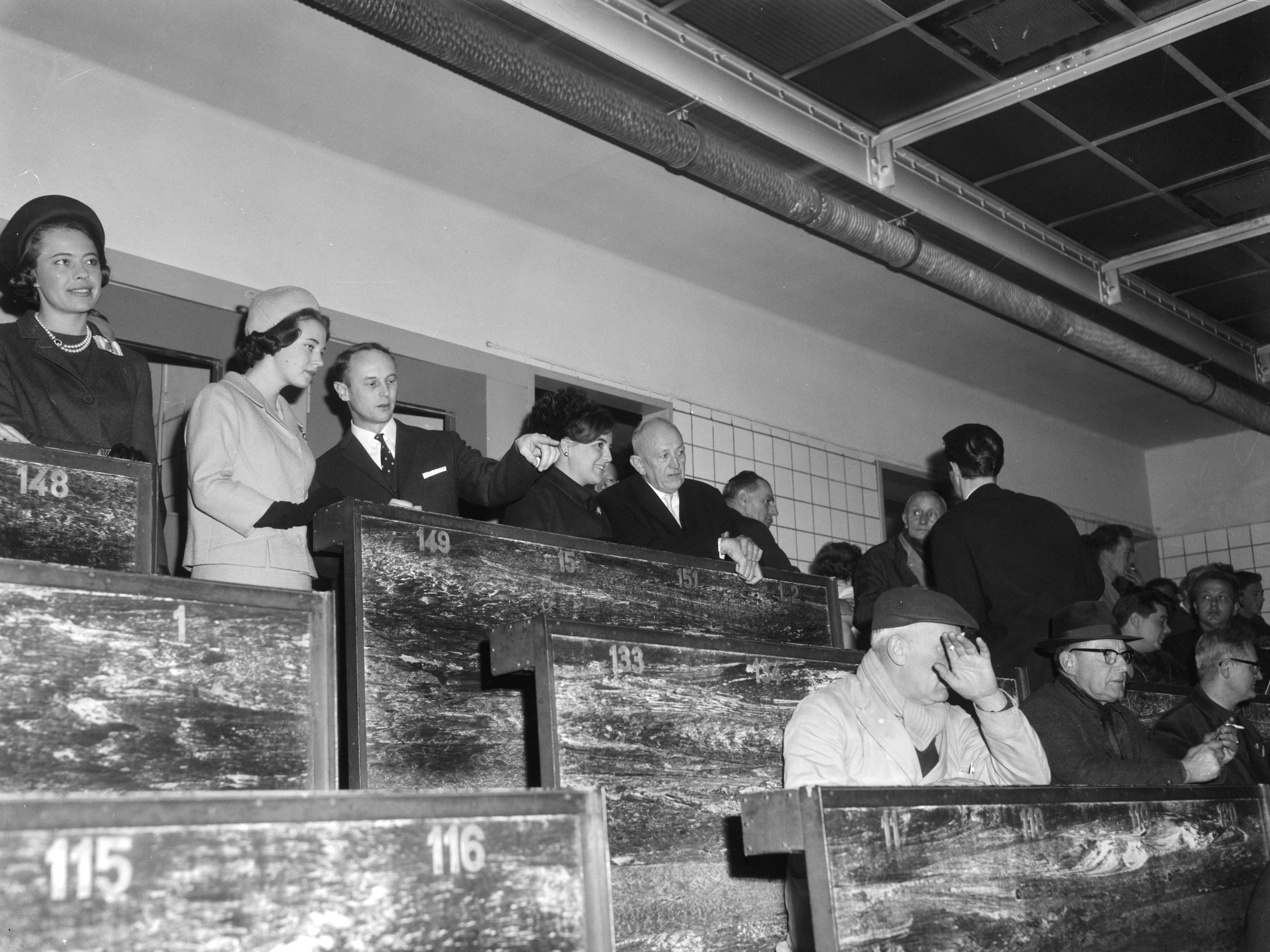 Bezoek van prinses Benedikte van Denemarken aan Nederland (1965) — De Deense prinses Benedikte en Prinses Margriet bezochten de bloemenveiling te Aalsmeer, de prinsessen tijdens de veiling. In het midden de voorzitter van de bloemenveiling dhr. Eveleens — Foto: Bilsen, Joop van / Anefo. Licentie: Set B: Rechtenvrij / Publiek Domein. Bron: Nationaal Archief. http://hdl.handle.net/10648/aa9e97ee-d0b4-102d-bcf8-003048976d84