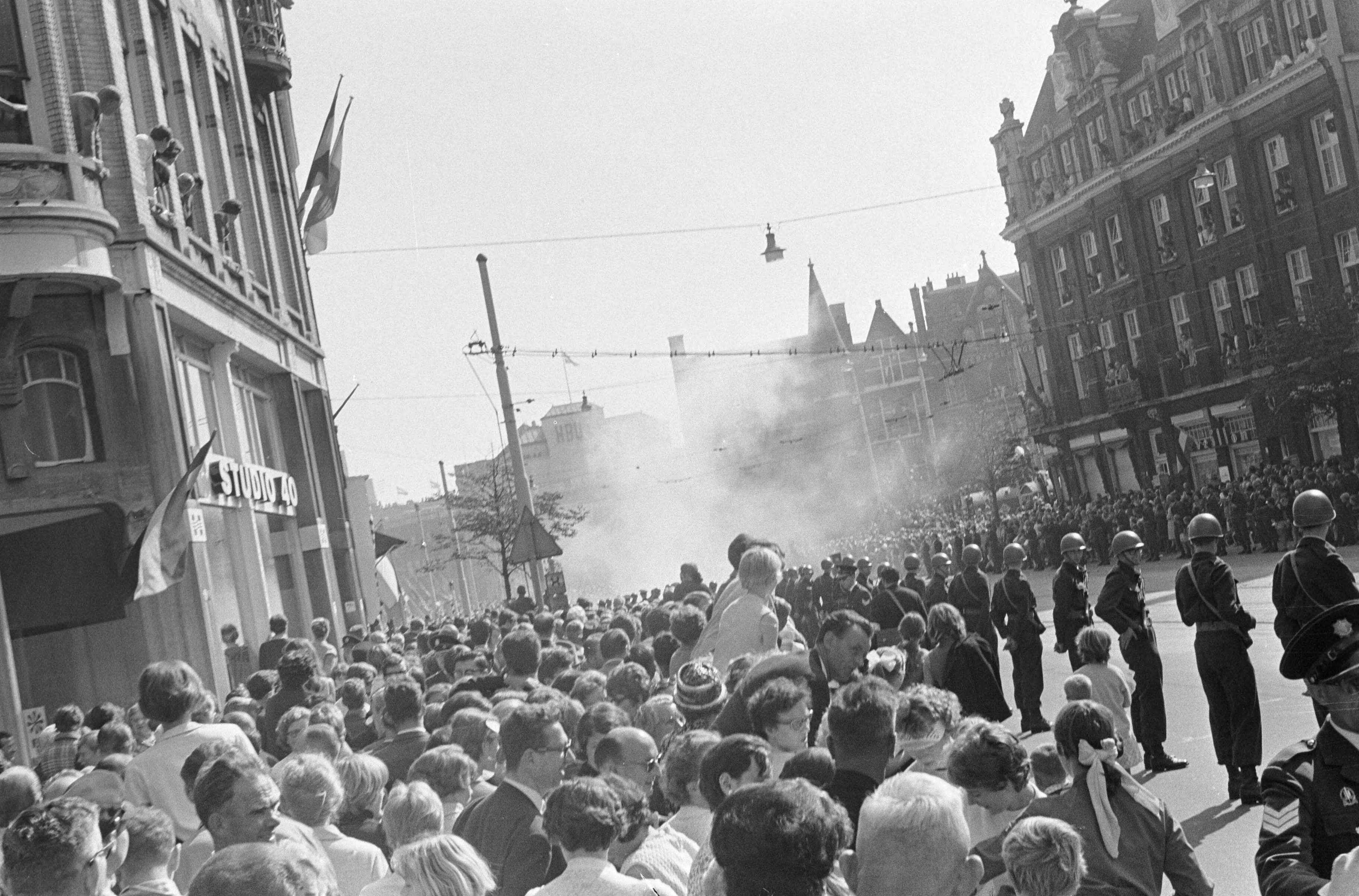 Protesterende Amsterdamse Provo's tijdens Prinsjesdag 1966 in Den Haag — Ontploffende rookbom binnen de afzetting — Foto: Fotograaf Onbekend / Anefo. Licentie: Set B: Rechtenvrij / Publiek Domein. Bron: Nationaal Archief. http://hdl.handle.net/10648/aafd3fec-d0b4-102d-bcf8-003048976d84