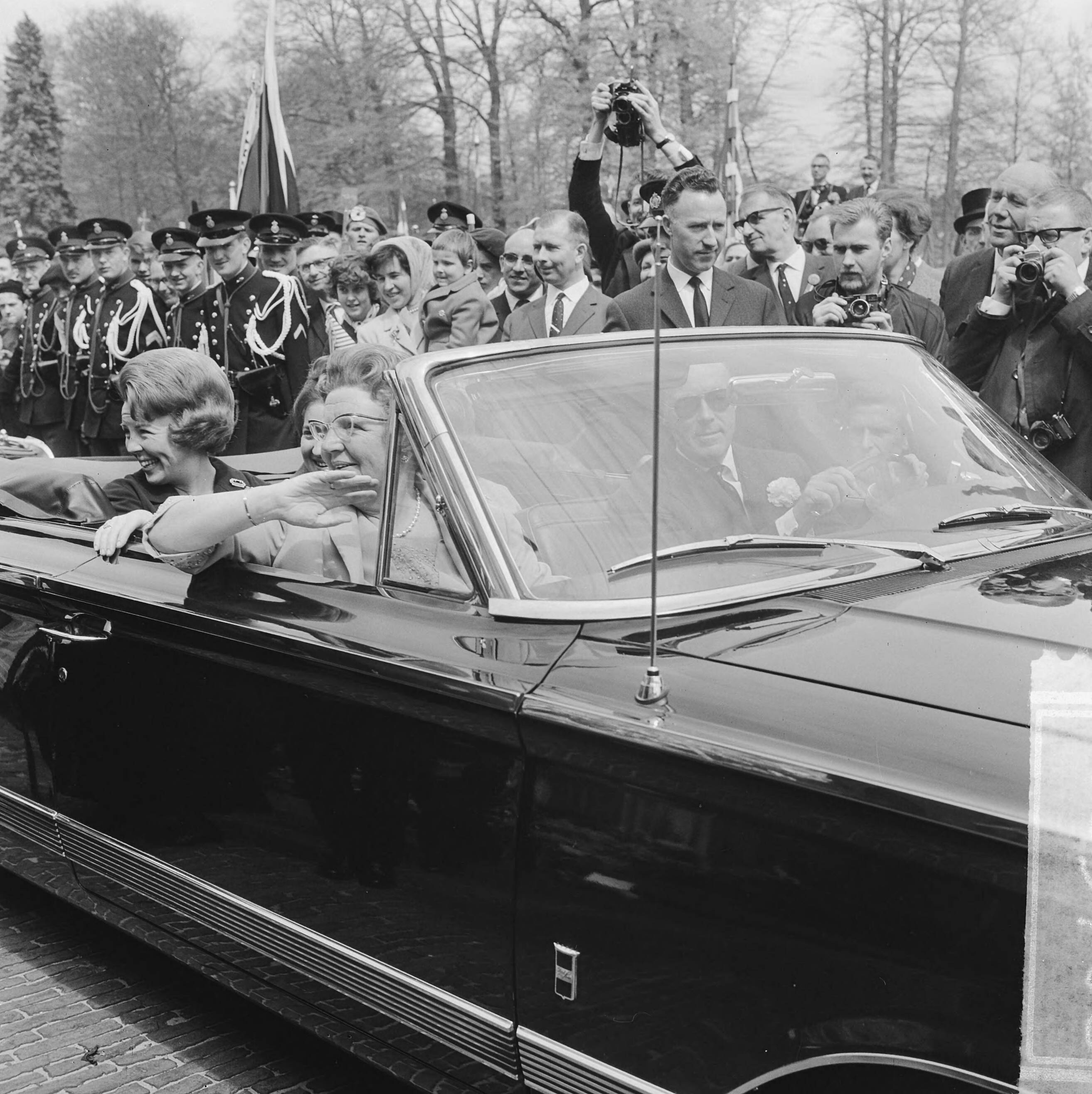 Koninginnedag 1964 — Defilé Soestdijk, tijdens autorit door paleistuin, voorin koningin Juliana en prins Bernhard, achterin de prinsessen Beatrix, Margriet en Christina — Foto: Koch, Eric / Anefo. Licentie: Set B: Rechtenvrij / Publiek Domein. Bron: Nationaal Archief. http://hdl.handle.net/10648/aa66c382-d0b4-102d-bcf8-003048976d84