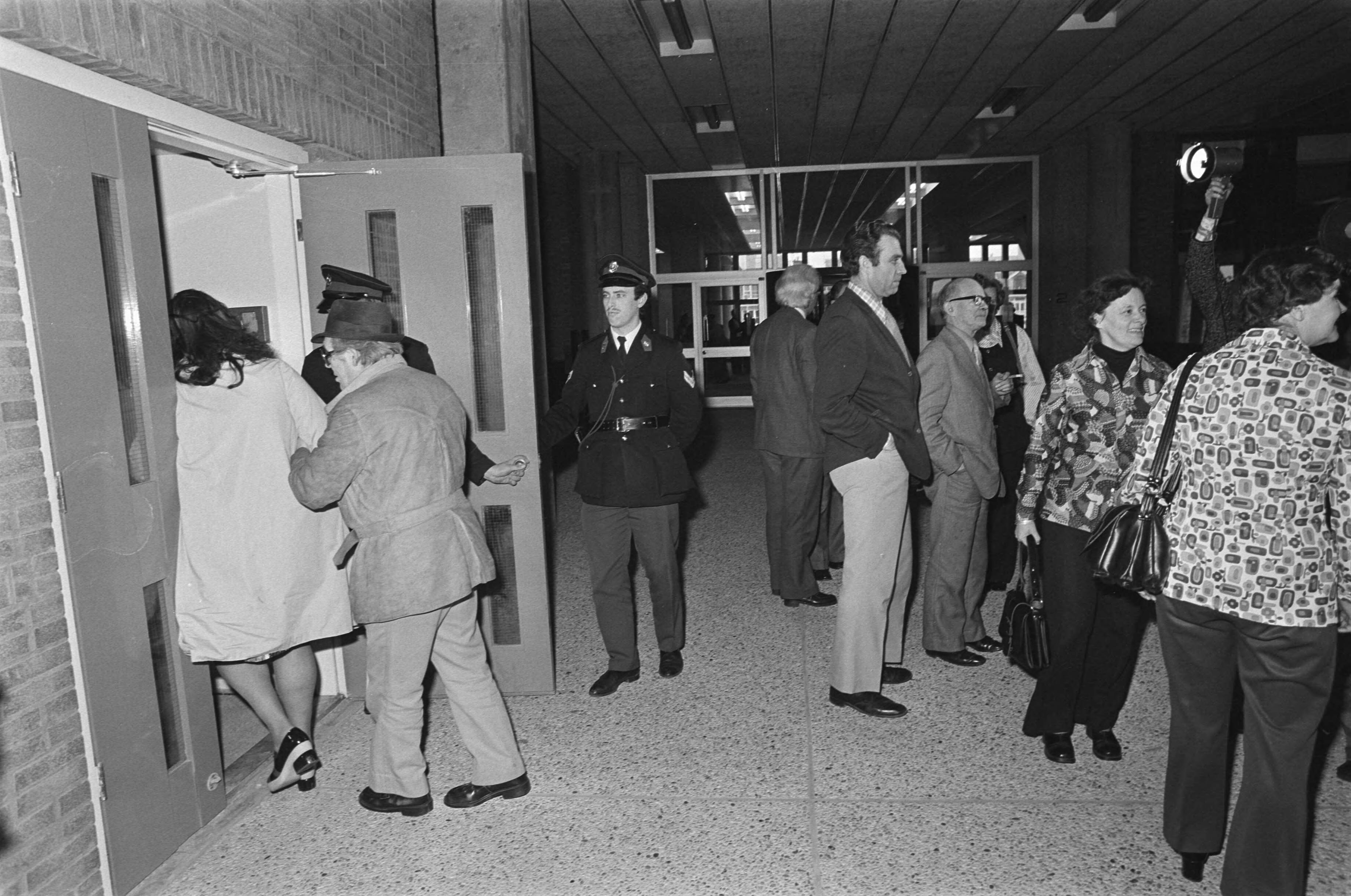 Fotocollectie Anefo — Verdachten Scheveningse gijzelingszaak voorgekomen in Den Haag ; leden koor bij ingang, heer en mw De Nie — Foto: Mieremet, Rob / Anefo. Licentie: Set B: Rechtenvrij / Publiek Domein. Bron: Nationaal Archief. http://hdl.handle.net/10648/ac627546-d0b4-102d-bcf8-003048976d84