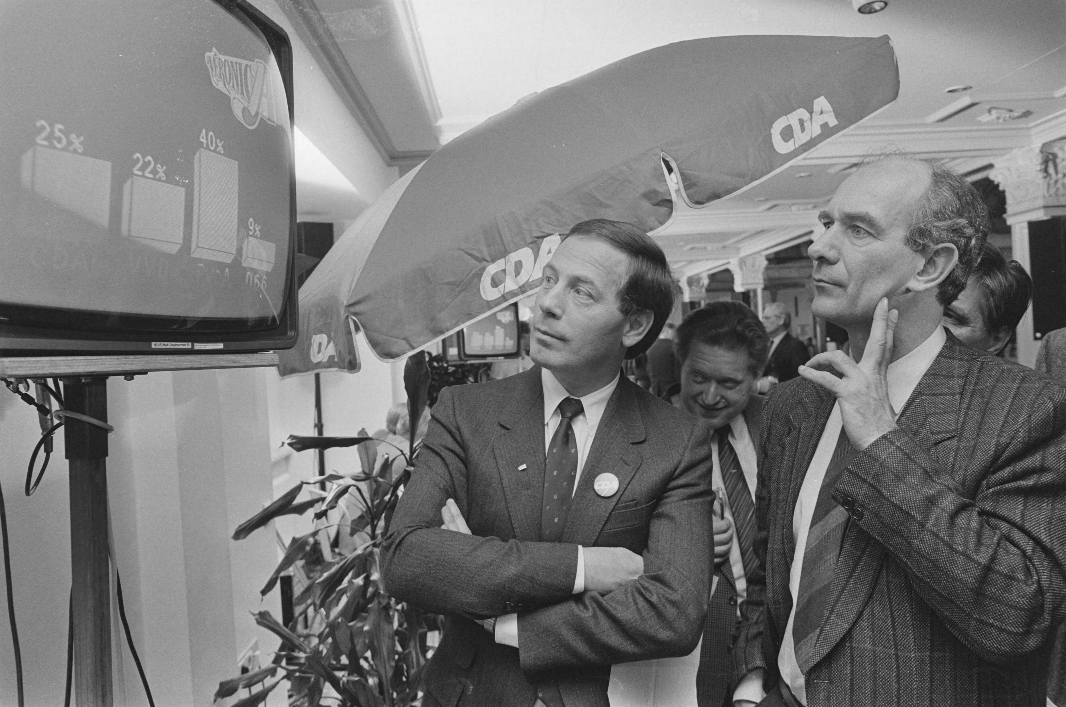 Fotocollectie Anefo — Provinciale Statenverkiezingen 1987; 26: premier Lubbers op verkiezingsuitslagenbijeenkomst in Scheveningen; 25: CDA-voorzitter Van Velzen (l) en — Foto: Croes, Rob C. / Anefo. Licentie: Set B: Rechtenvrij / Publiek Domein. Bron: Nationaal Archief. http://hdl.handle.net/10648/ad5e055a-d0b4-102d-bcf8-003048976d84