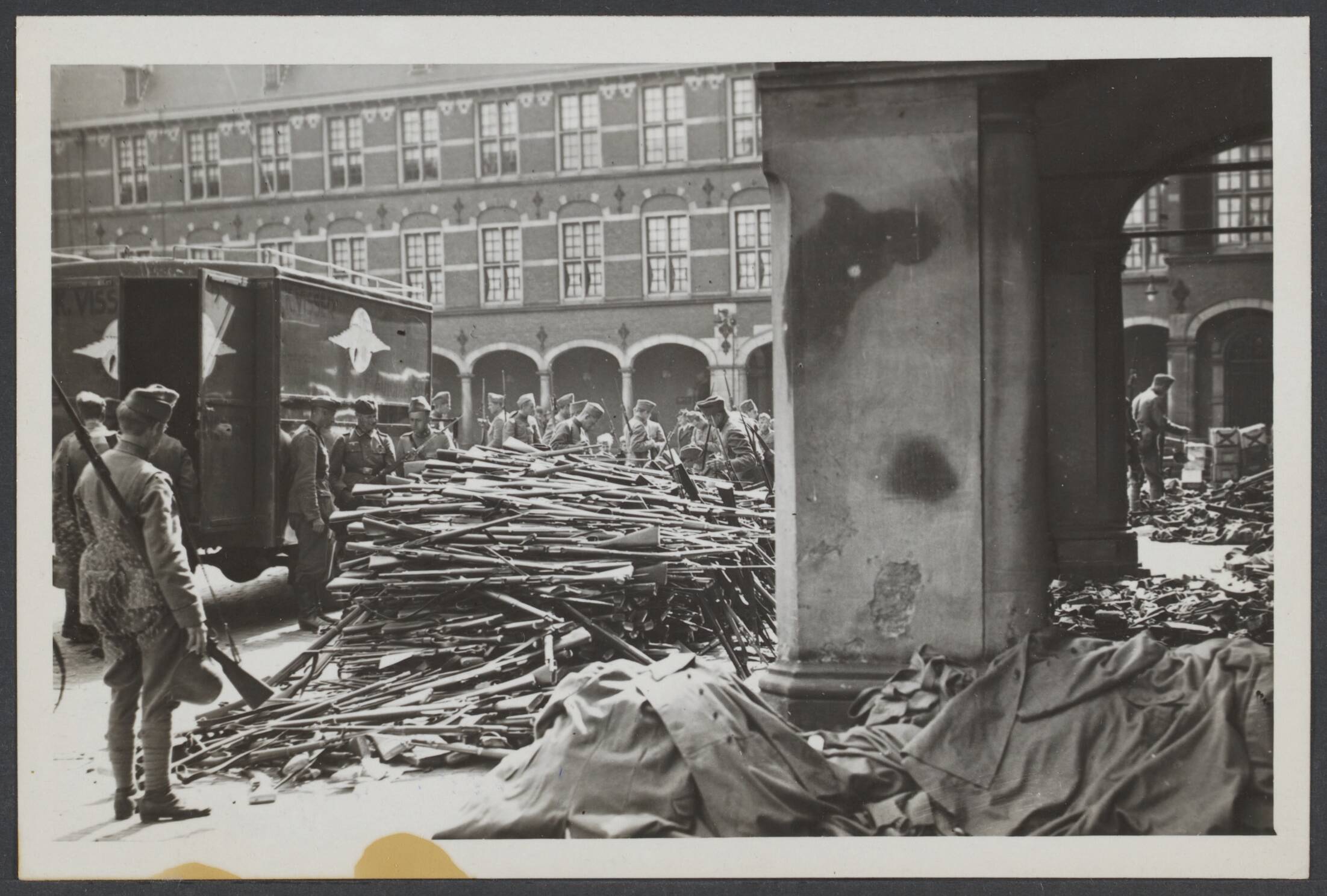 Demobilisatie 1940 — De strijd is gestaakt. Nederlandse soldaten bij een inleverplaats van wapens op het Binnenhof te Den Haag — Foto: N.V. Vereenigde Fotobureaux. Licentie: Set B: Rechtenvrij / Publiek Domein. Bron: Nationaal Archief. http://hdl.handle.net/10648/d1d772f7-d757-64e4-d572-9aa41afa7622