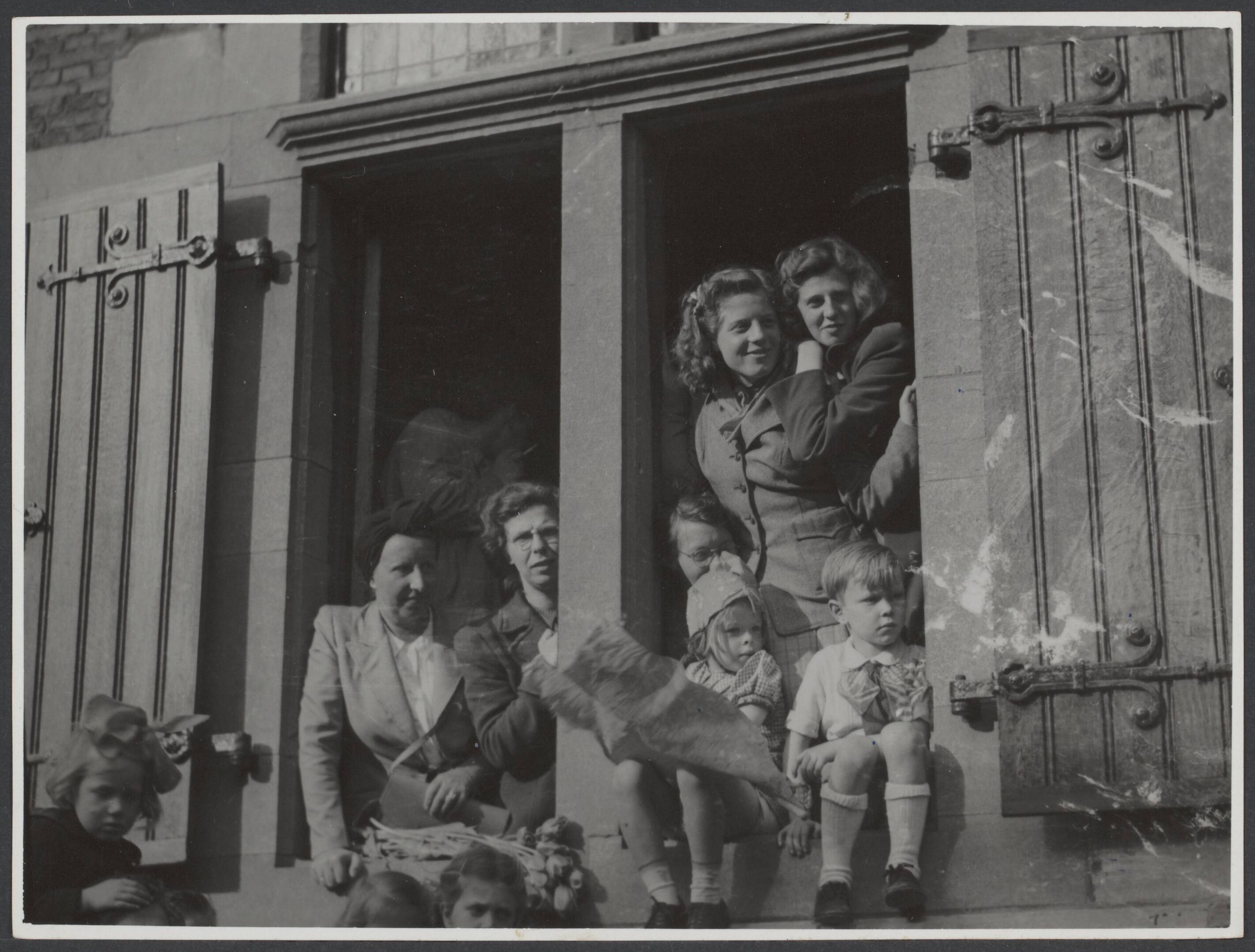 Bevrijding 's Gravenhage (Den Haag) — Belangstellenden (vrouwen en kinderen) staan en zitten in de vensters van het Haagse stadhuis, tijdens de intocht der Canadezen te Den Haag — Foto: Wal, J.Th. A. van der / Spaarnestad. Licentie: Set B: Rechtenvrij / Publiek Domein. Bron: Nationaal Archief. http://hdl.handle.net/10648/cd5b2801-47c2-4800-ae2f-97becf3f6823