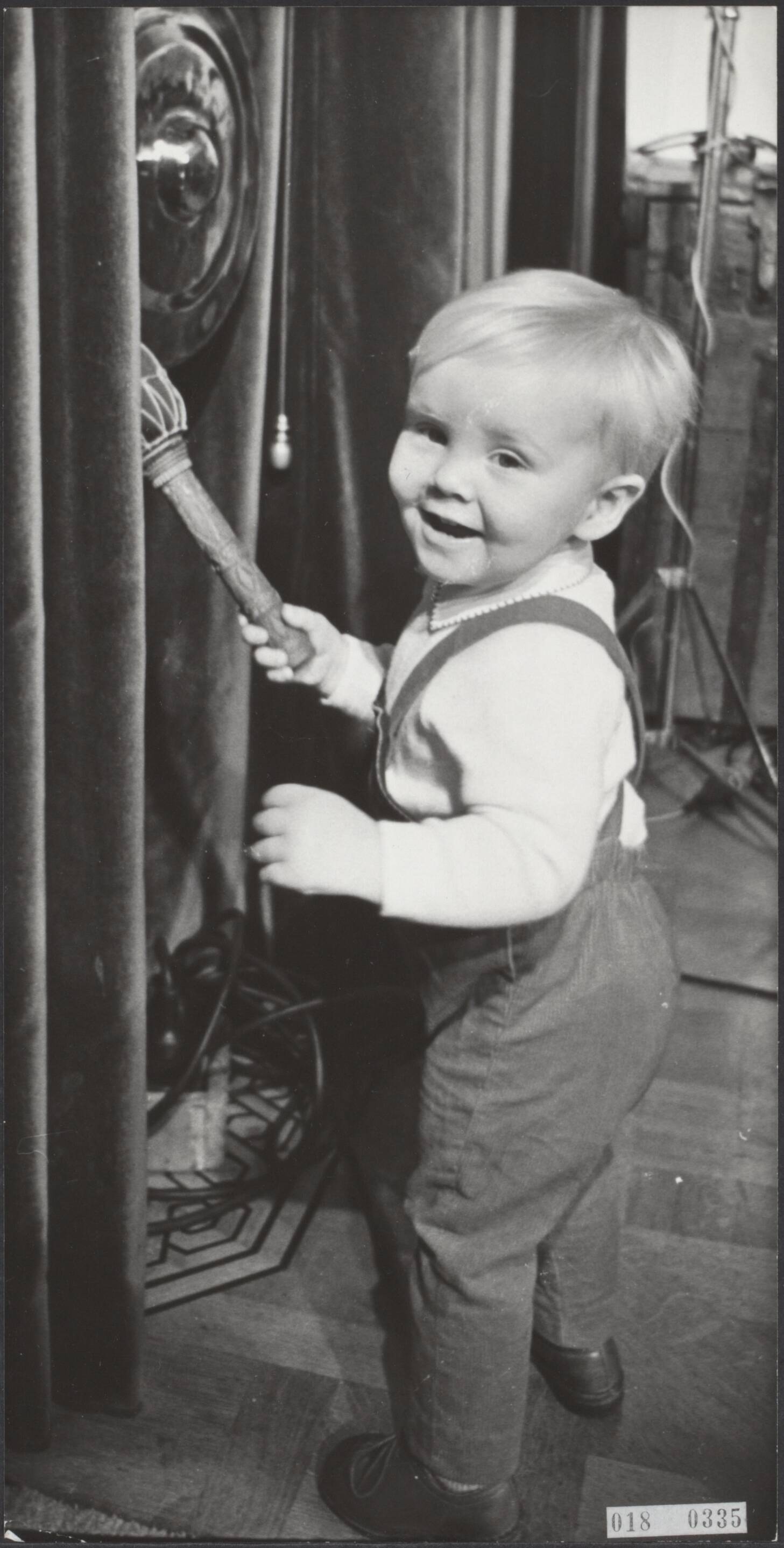 Fotocollectie Elsevier Binnenland — Door prinses Beatrix is op kasteel Drakensteyn aan een commissie voor gehandicapte kinderen, die een revalidatiecentrum in Suriname willen bouwen, een som gelds overhandigd. Dit bedrag ontving de prinses indertijd n.a.v. haar huwelijk om het te besteden voor en door haar te bepalen doel. Prins Willem-Alexander vermaakte zich intussen met de gong in de hal — Foto: Fotograaf Onbekend / Anefo. Licentie: Set B: Rechtenvrij / Publiek Domein. Bron: Nationaal Archief. http://hdl.handle.net/10648/adc1efde-d0b4-102d-bcf8-003048976d84