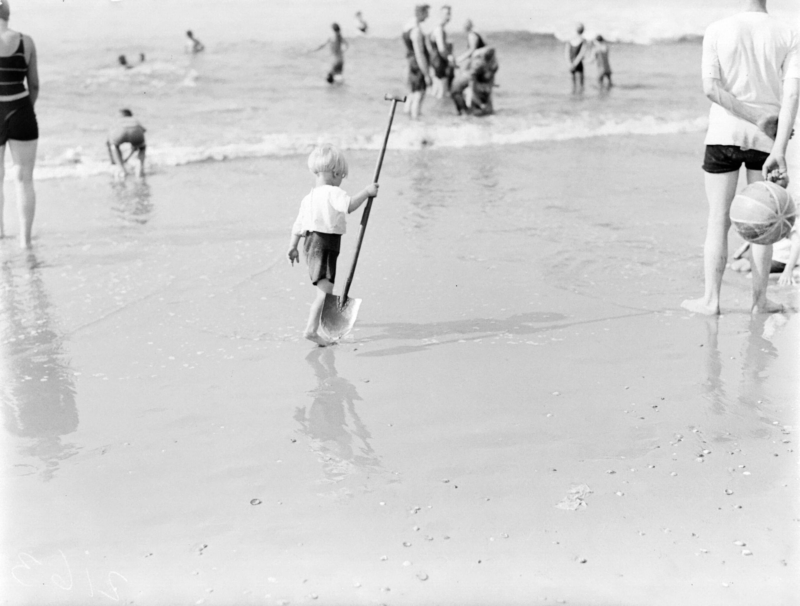 Scheveningen. — Een kind met schop op het strand in Scheveningen — Foto: Poll, Willem van de. Licentie: Set B: Rechtenvrij / Publiek Domein. Bron: Nationaal Archief. http://hdl.handle.net/10648/aea9f374-d0b4-102d-bcf8-003048976d84