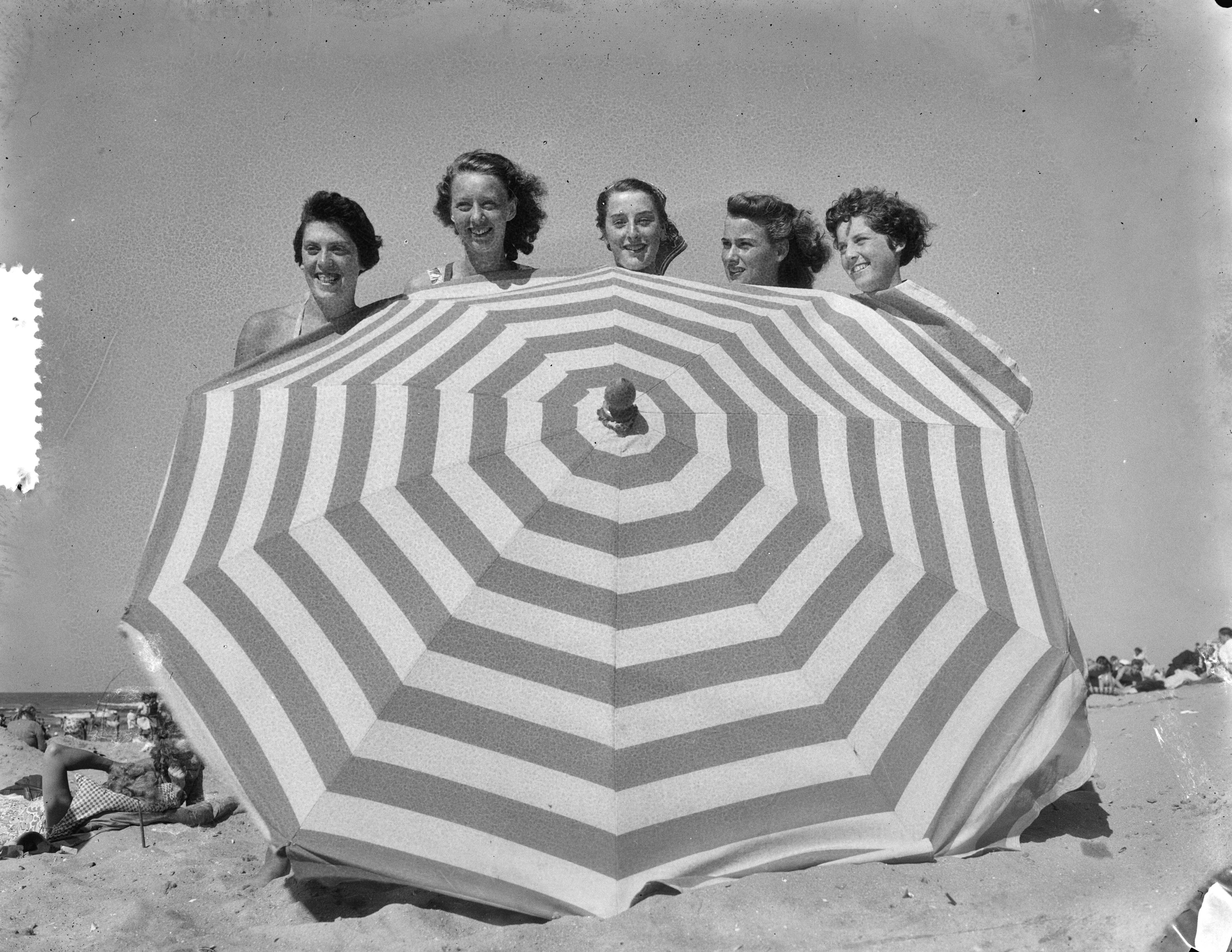 Fotocollectie Anefo — Strandplaatjes Scheveningen. Parasol en badschonen — Foto: Consenheim, Wim / Anefo. Licentie: Set B: Rechtenvrij / Publiek Domein. Bron: Nationaal Archief. http://hdl.handle.net/10648/a8fe4da8-d0b4-102d-bcf8-003048976d84