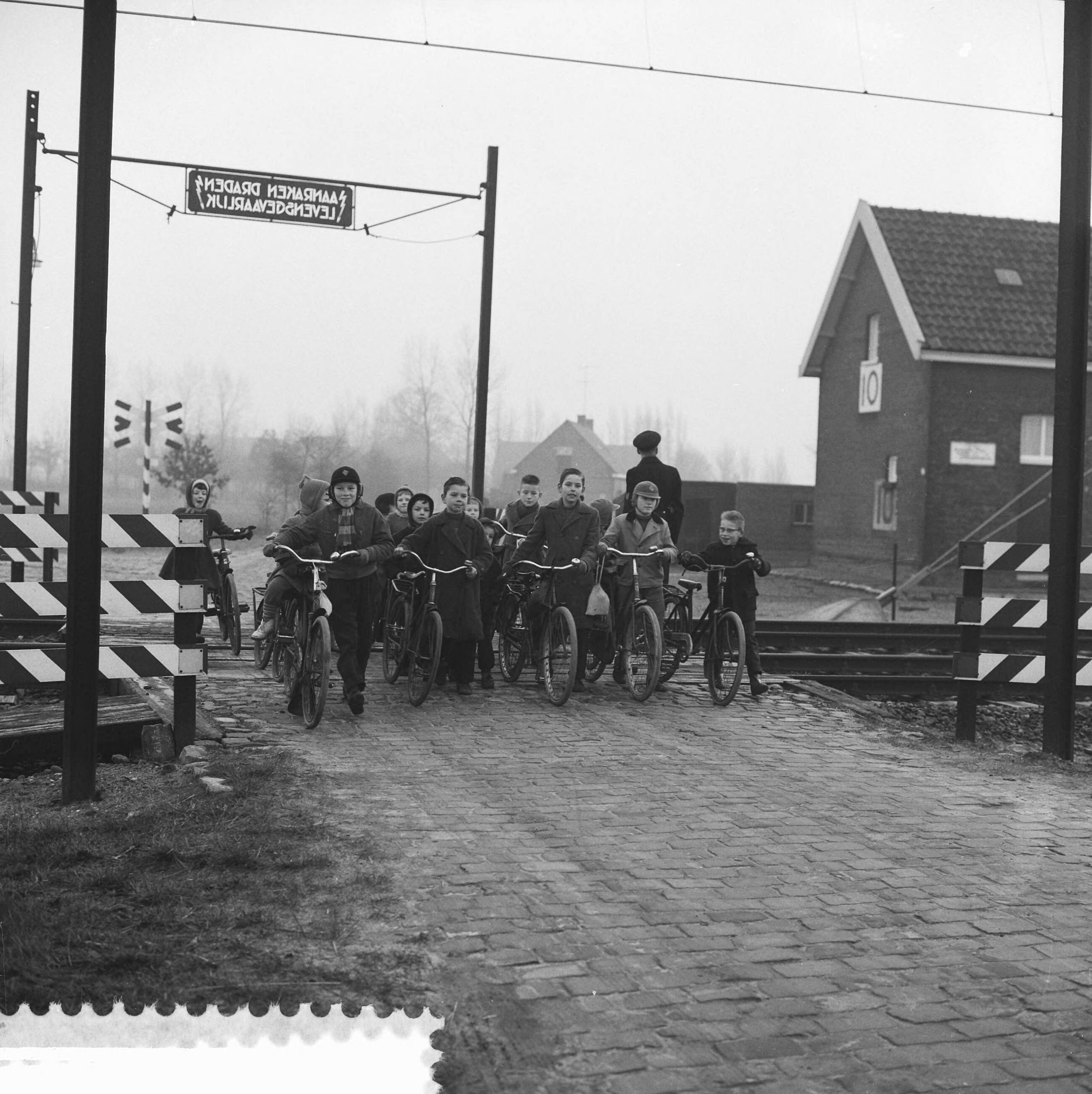 Fotocollectie Anefo — Politiebewaking bij spoorwegovergang in Prinsenbeek. Schoolkinderen met fietsen aan de hand steken over — Foto: Chabot, Hans / Anefo. Licentie: Set B: Rechtenvrij / Publiek Domein. Bron: Nationaal Archief. http://hdl.handle.net/10648/a9a74a70-d0b4-102d-bcf8-003048976d84
