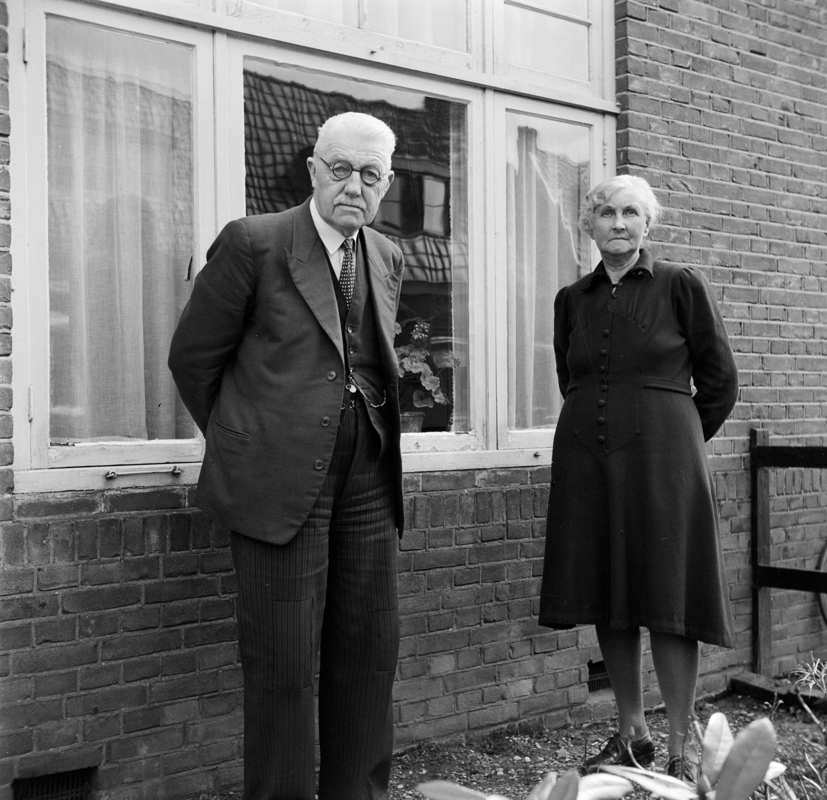Fotocollectie Van de Poll — Het echtpaar S. de Jong in de tuin voor hun woning in het Friese Huizum (nu deel van Leeuwarden) — Foto: Poll, Willem van de. Licentie: Set B: Rechtenvrij / Publiek Domein. Bron: Nationaal Archief. http://hdl.handle.net/10648/aeccc444-d0b4-102d-bcf8-003048976d84