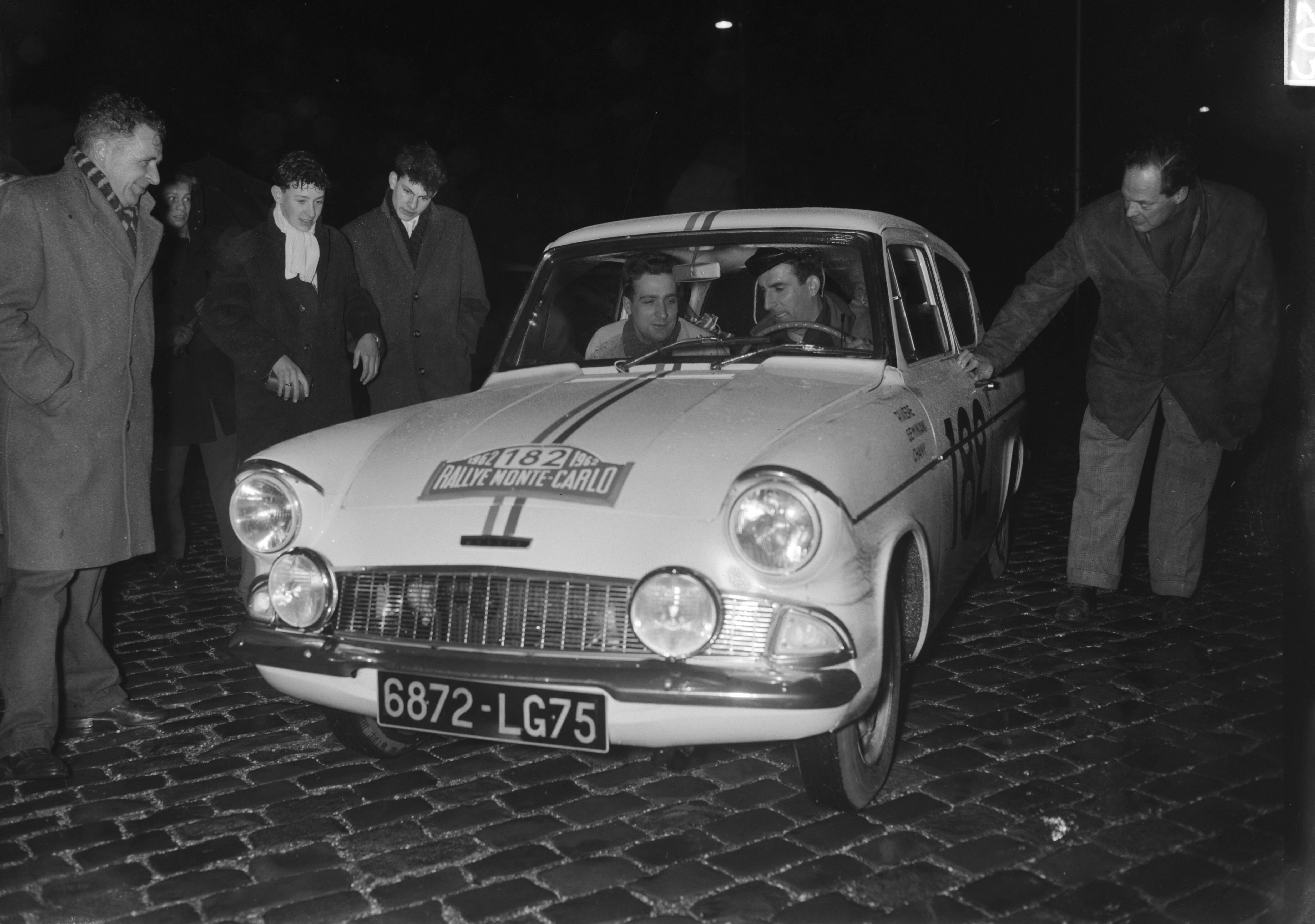 Fotocollectie Anefo — Deelnemers Rally Monte Carlo tijdcontrole in Scheveningen. Roger Riviere en Geminiani Raphaël met Ford Anglia (startnummer 182) — Foto: Bilsen, Joop van / Anefo. Licentie: Set B: Rechtenvrij / Publiek Domein. Bron: Nationaal Archief. http://hdl.handle.net/10648/a9f4f91e-d0b4-102d-bcf8-003048976d84