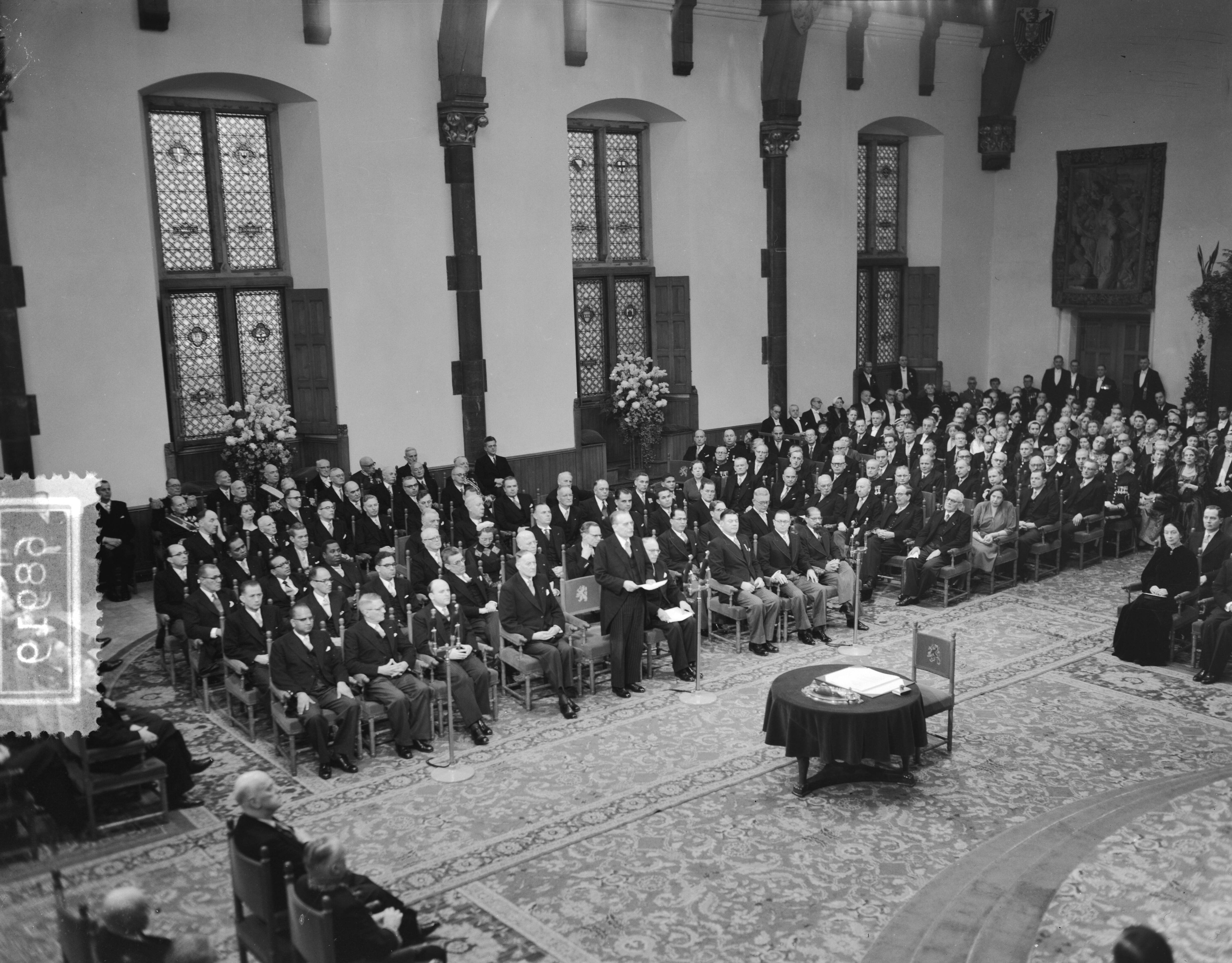 Koningin Juliana ondertekent in een plechtige bijeenkomst in de Ridderzaal in Den Haag de Acte van Bevestiging van het Statuut voor het Koninkrijk — Ondertekening van de Acte van Bevestiging van het Statuut van het Koninkrijk in de Ridderzaal te Den Haag. Één van de ministers houdt een toespraak — Foto: Noske, J.D. / Anefo. Licentie: Set B: Rechtenvrij / Publiek Domein. Bron: Nationaal Archief. http://hdl.handle.net/10648/a92e1bbe-d0b4-102d-bcf8-003048976d84