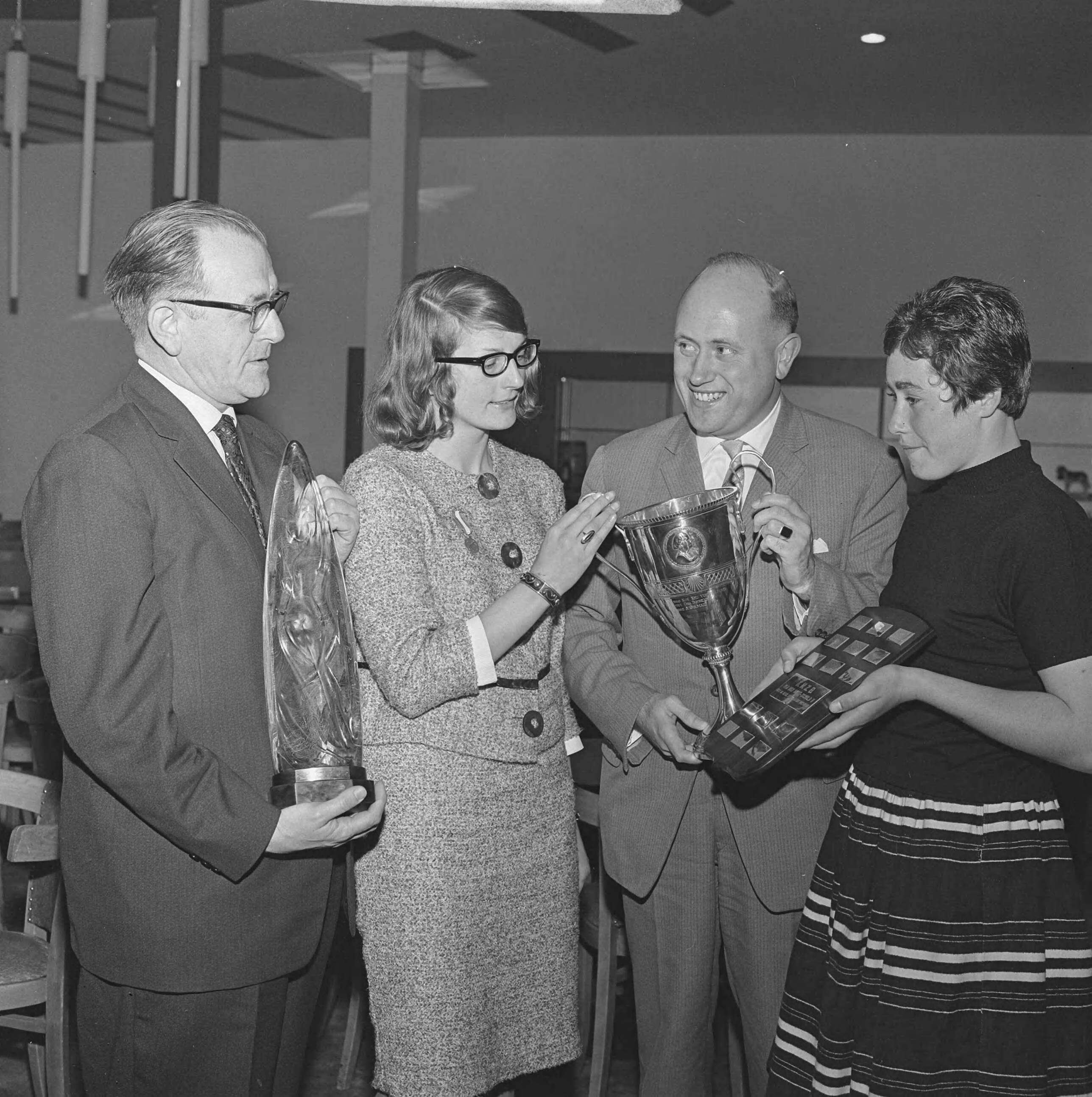 Fotocollectie Anefo — Uitreiking onderscheidingen op de jaarvergadering van de KNZB. Vlnr. Jan Armbrust, echtgenote van de overleden Uut Molenaar, leidster van de zwemvereniging Admiraal de Ruyter met de nieuwe trofee, de Uut Armbrust-Molenaar Memorial, de Groningse rugslagzwemster Corrie Winkel kreeg de gouden penning van verdienste, aftredend voorzitter van de Sportcommissie S. Bolman met de Moeder Triebels beker en Adrie Lasterie, vrije slagzwemster van de zwemvereniging Naarden met het Van der Mastschild en een gouden medaille — Foto: Koch, Eric / Anefo. Licentie: Set B: Rechtenvrij / Publiek Domein. Bron: Nationaal Archief. http://hdl.handle.net/10648/aa046002-d0b4-102d-bcf8-003048976d84