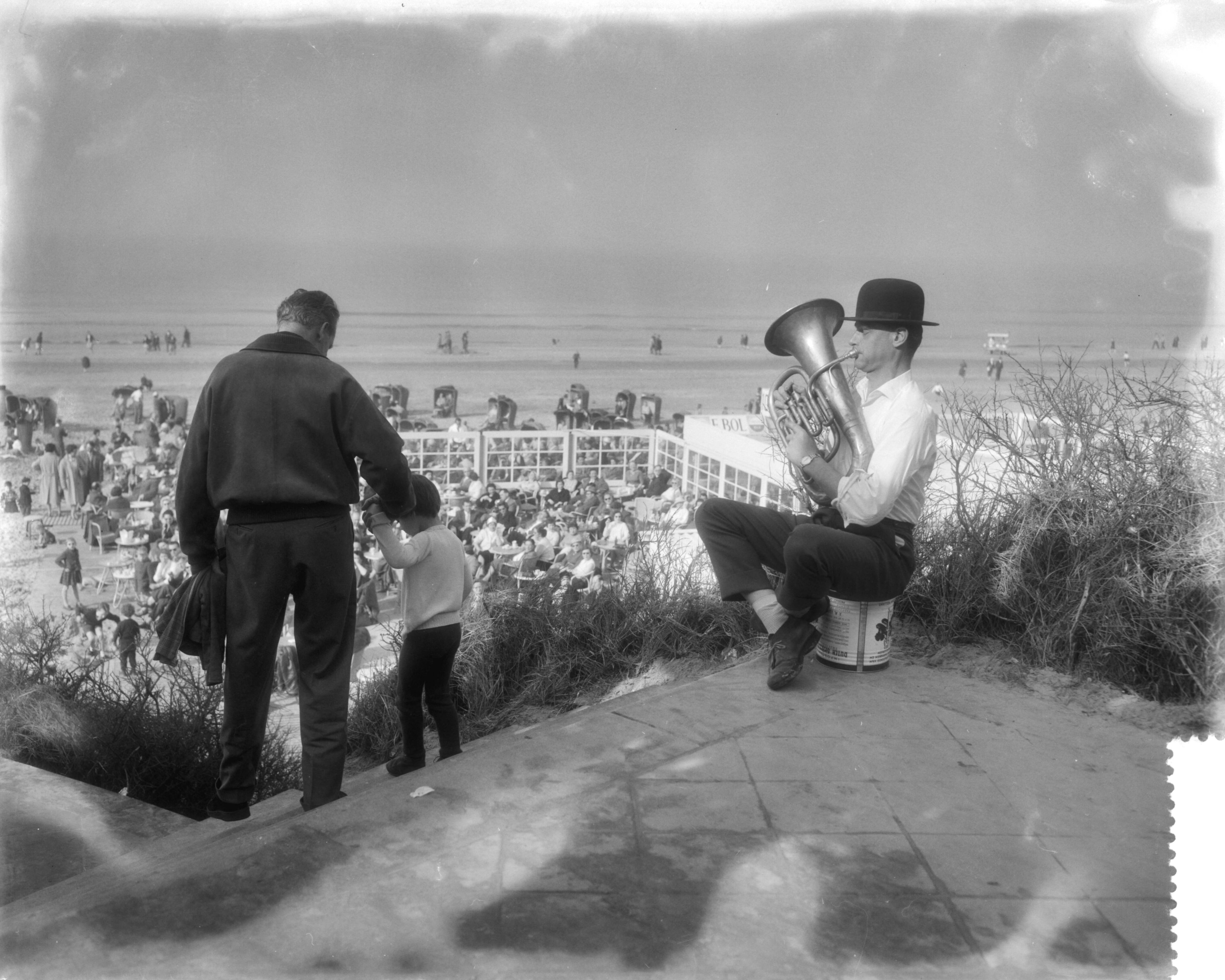 Fotocollectie Anefo — Drukte aan het strand te Zandvoort i.v.m. het mooie weer. Muzikant met tuba en bolhoed — Foto: Pot, Harry / Anefo. Licentie: Set B: Rechtenvrij / Publiek Domein. Bron: Nationaal Archief. http://hdl.handle.net/10648/a98eaf88-d0b4-102d-bcf8-003048976d84