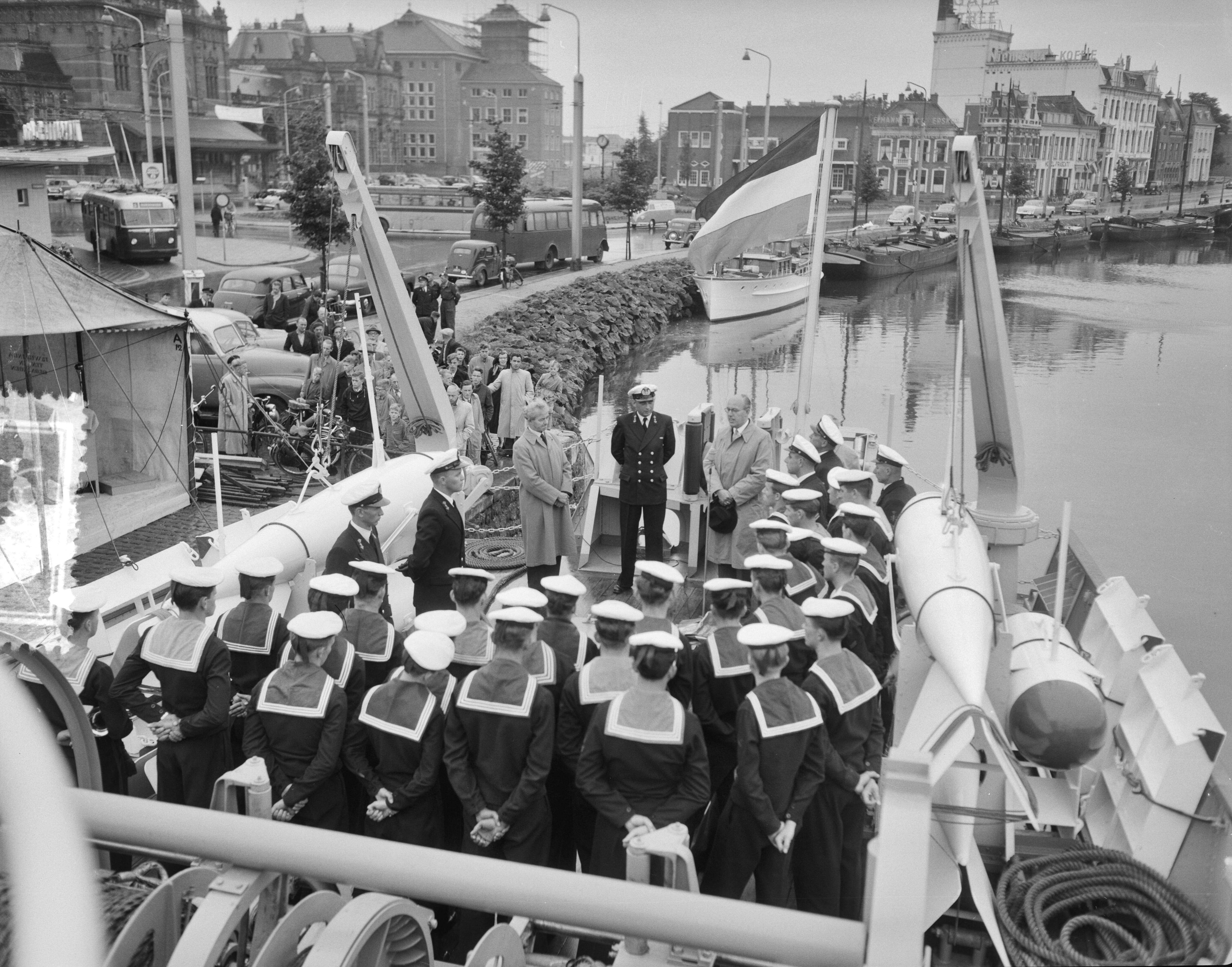 Overdracht en indienststelling van de kustmijnenveger Hr. Ms. "Lochem" in het Verbindingskanaal te Groningen — Overdracht en indienststelling van de kustmijnenveger Hr. Ms. "Lochem" in het Verbindingskanaal te Groningen. Toespraak op het achterdek door de burgemeester van Lochem, H.A. Beusekamp. In het midden de commandant, luitenant-ter-zee 2e klasse D. Lindner — Foto: Behrens, Herbert F. / Anefo. Licentie: Set B: Rechtenvrij / Publiek Domein. Bron: Nationaal Archief. http://hdl.handle.net/10648/a94bb872-d0b4-102d-bcf8-003048976d84